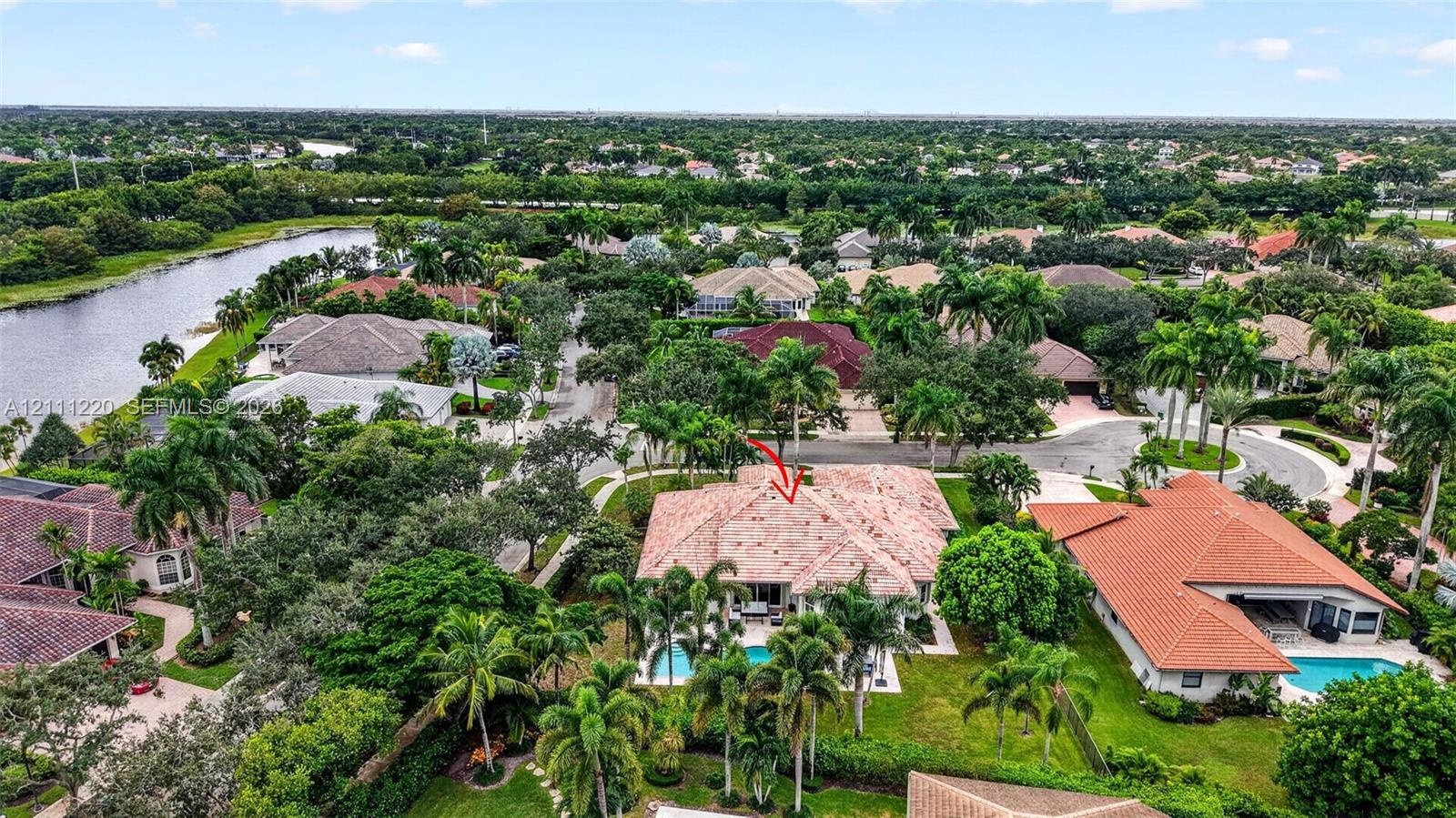 Aerial perspective of a property featuring a tile roof, an in-ground swimming pool, and mature landscaping