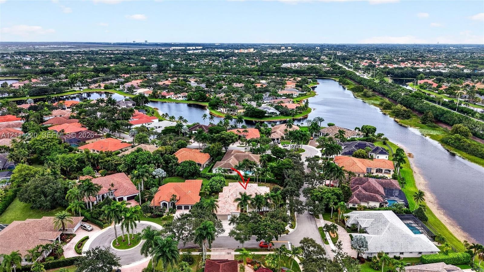 Aerial perspective of a residential property situated in a planned community featuring tile roofing, mature landscaping, and proximity to regional wat