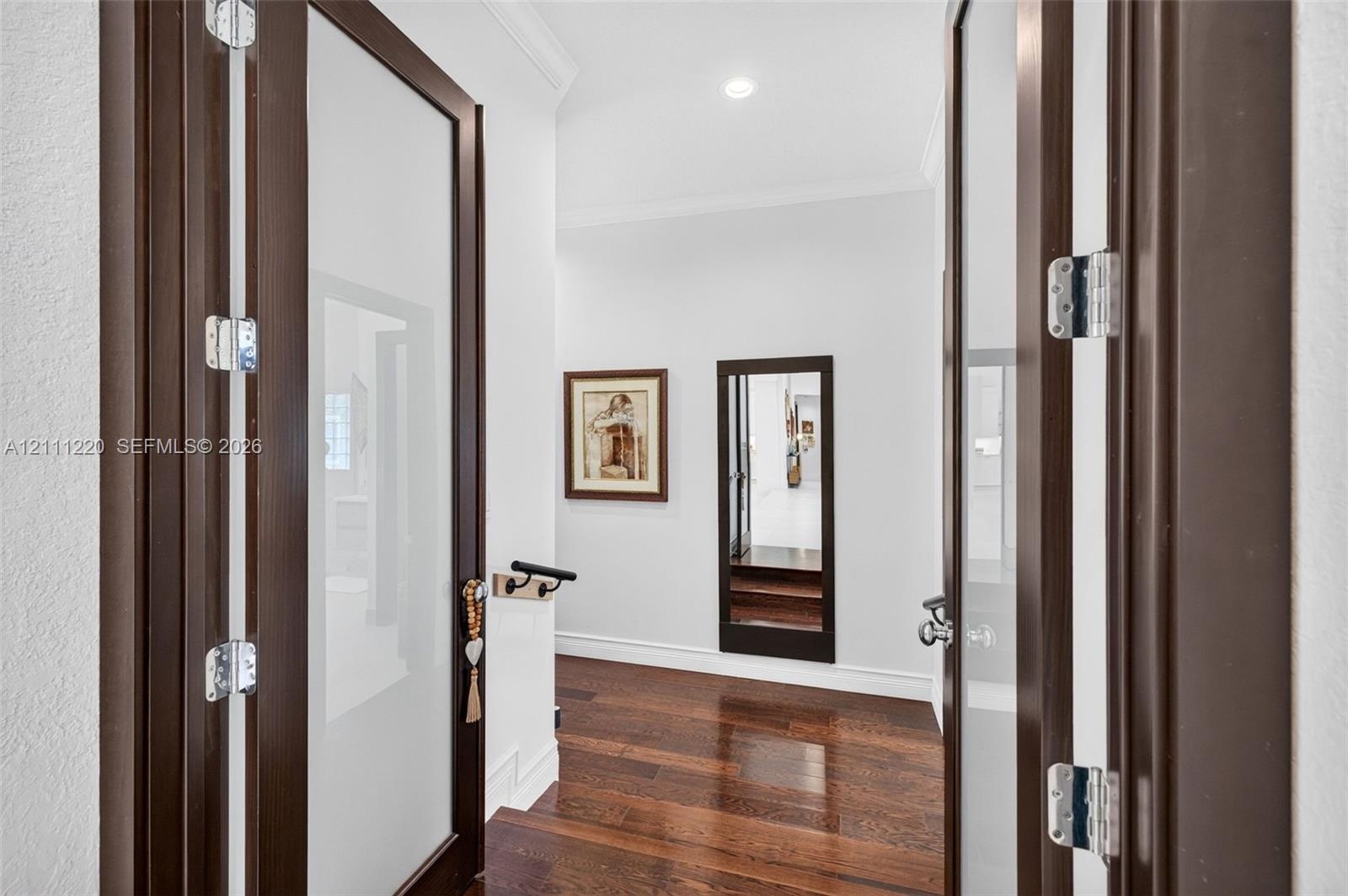 Double doors featuring dark wood frames with frosted glass panels, wood-finish flooring, and recessed ceiling lighting