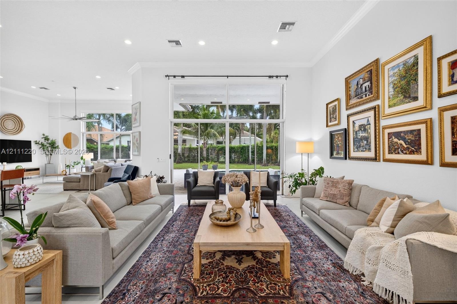 Open-concept interior featuring high ceilings, recessed lighting, neutral tile flooring, and oversized glass sliding doors