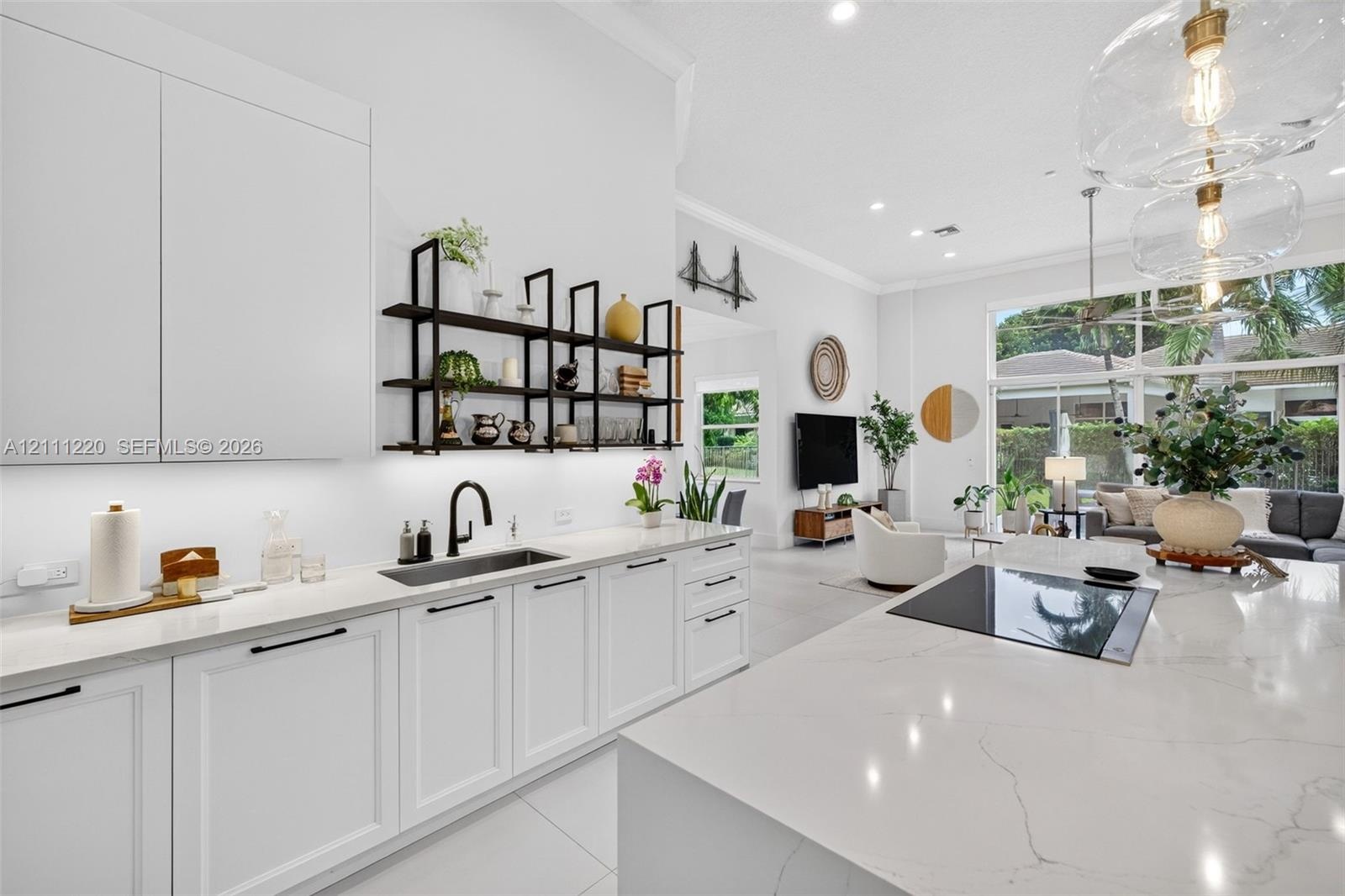 Kitchen featuring white shaker-style cabinetry, a large central island with a solid surface countertop, matte black hardware, under-cabinet lighting, 