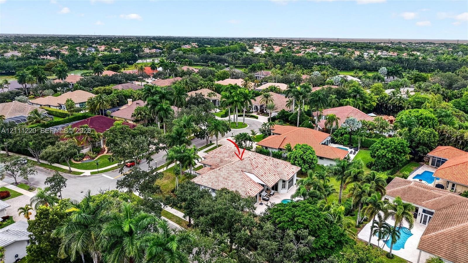 Aerial perspective of a residential property featuring a tiled roof, multi-car garage, and mature landscaping in a suburban setting