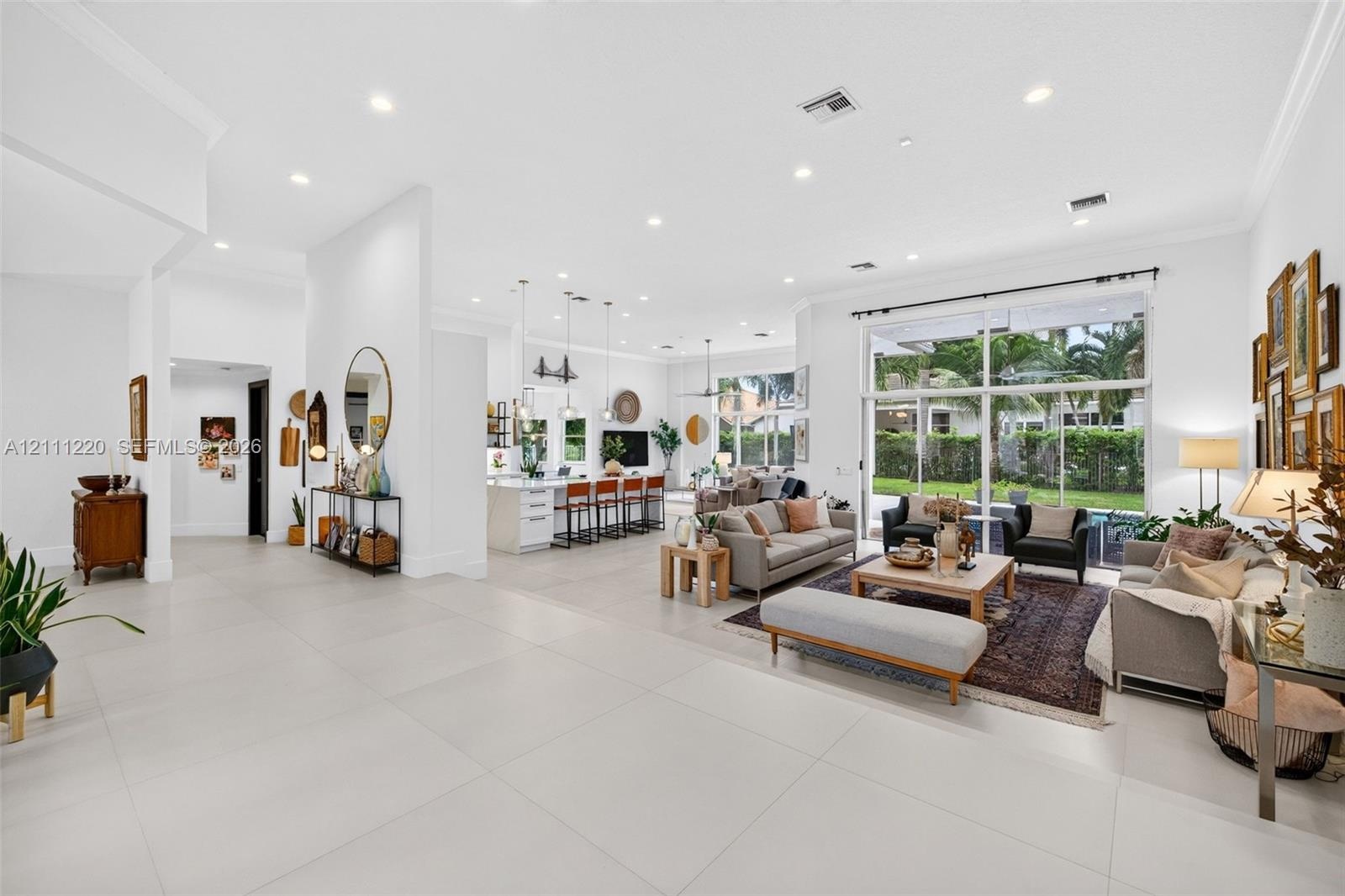 Open-concept living space featuring oversized neutral floor tile, recessed lighting, crown molding, and expansive floor-to-ceiling glass panel windows