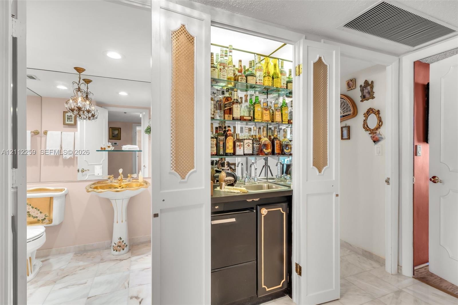 Built-in wet bar featuring glass shelving, mirrored backsplash, and under-counter cabinetry