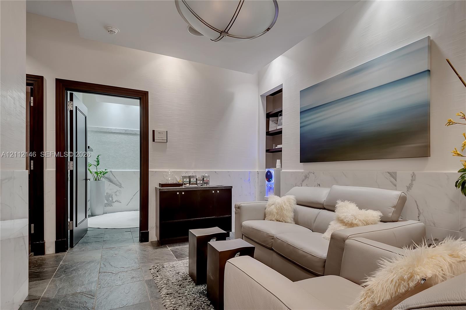 Stone tile flooring, wainscoting with integrated stone-finish panels, recessed shelving, and a spherical semi-flush mount light fixture