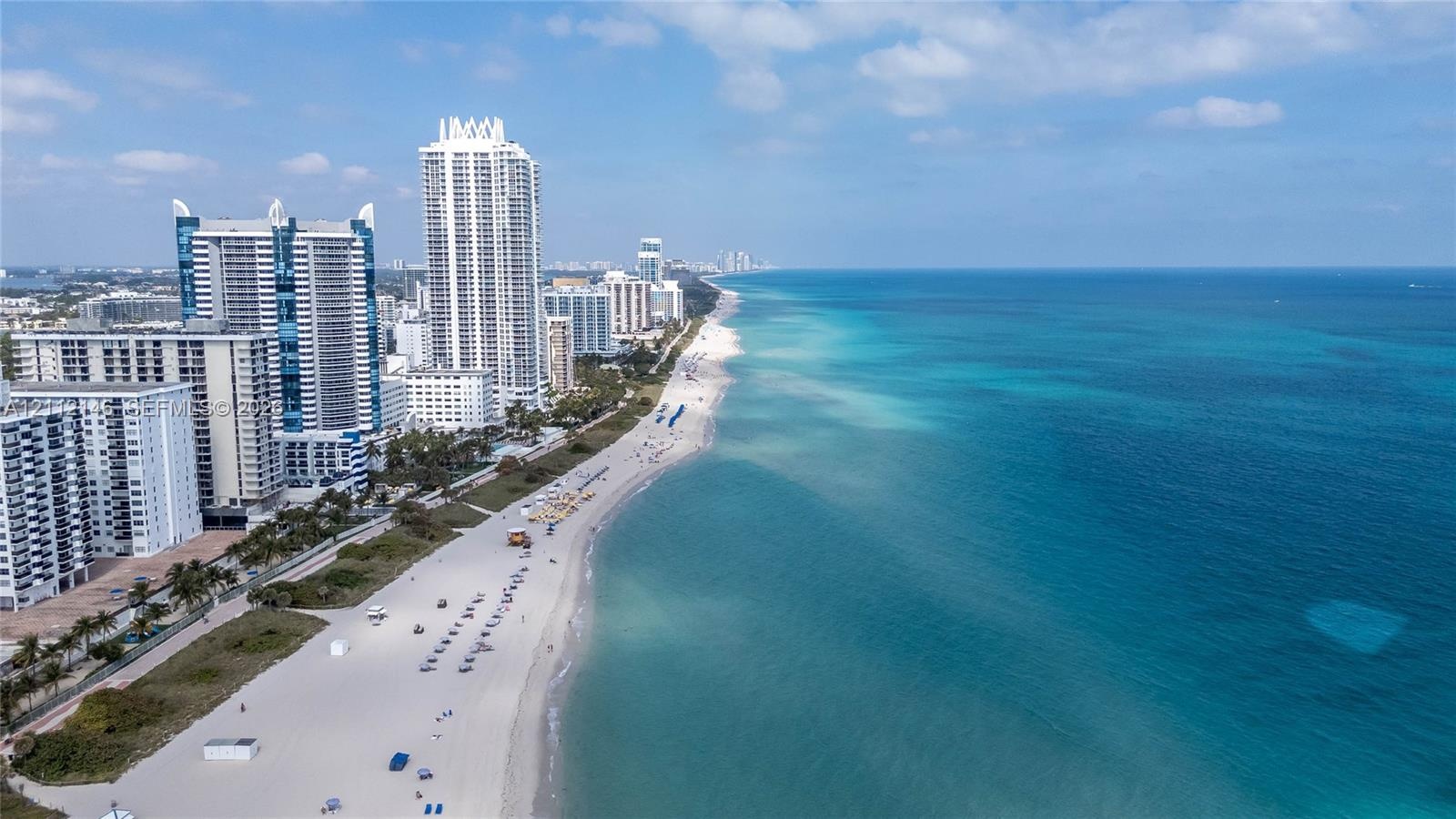 Aerial perspective featuring a stretch of sandy shoreline and turquoise coastal waters