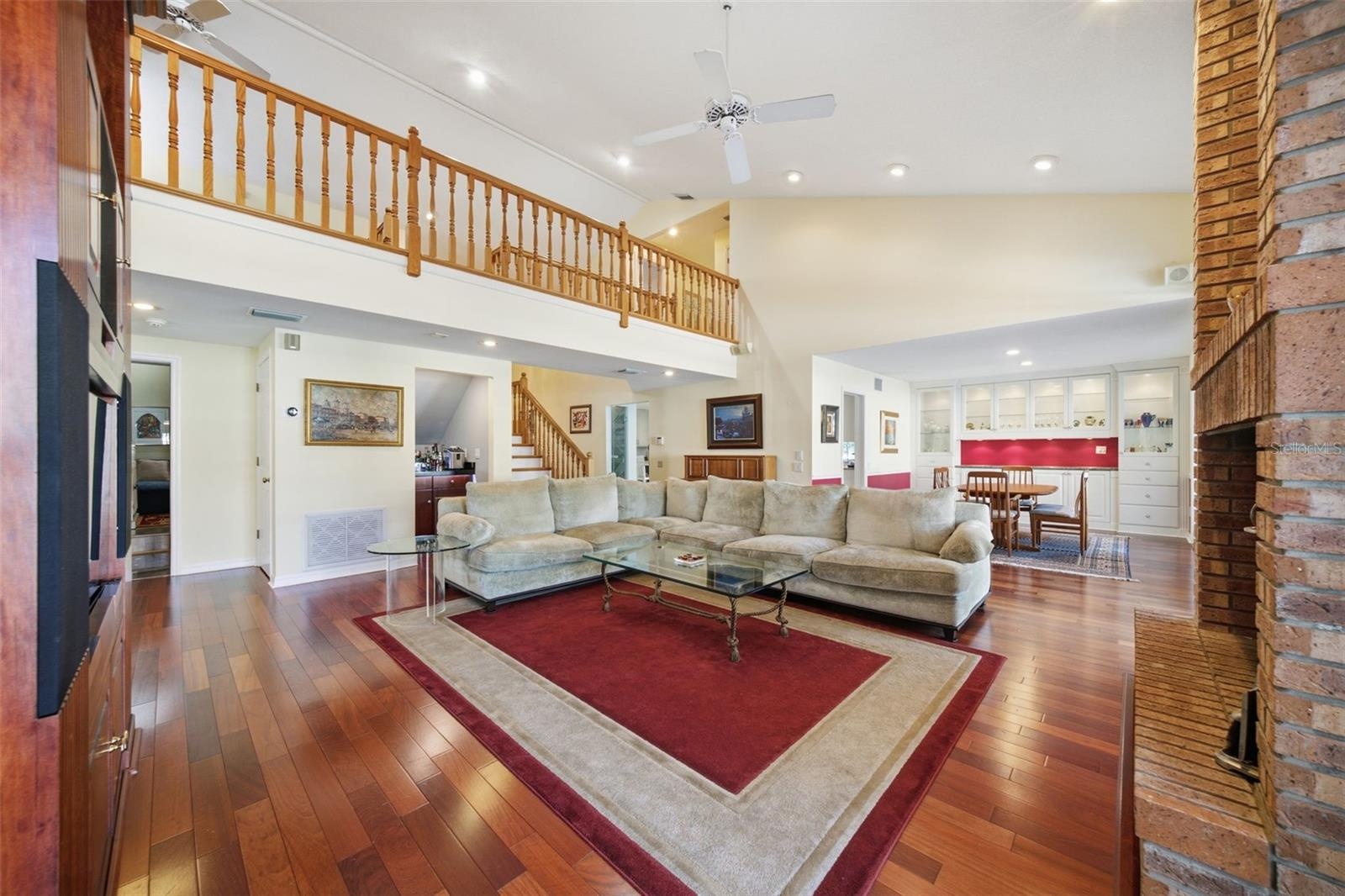 Expansive Family Room with a view of the Dining Room and second floor gallery. Wood-burning brick fireplace
