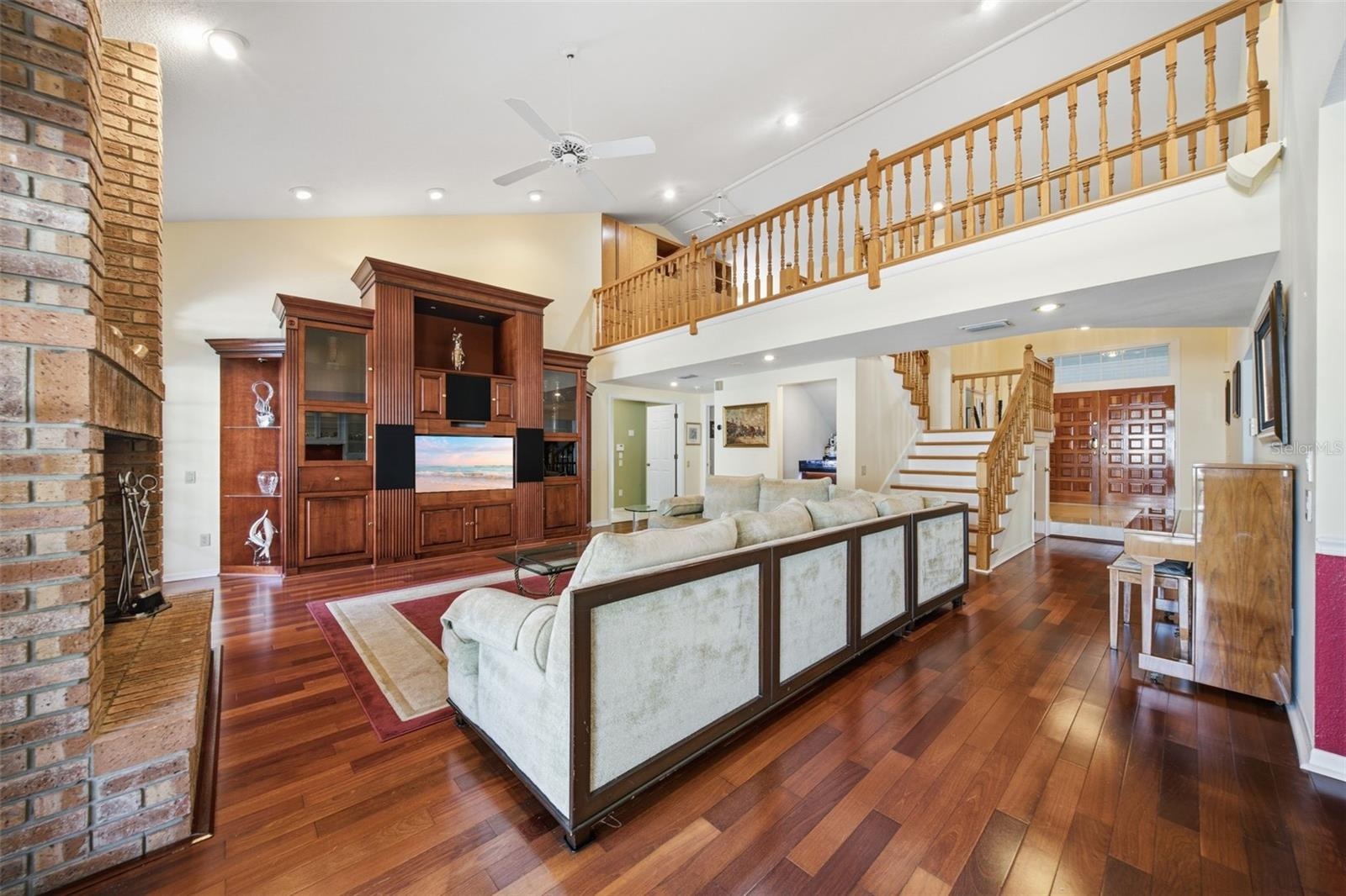Great Room with wood flooring, built-ins and view to the Gallery / Loft area above