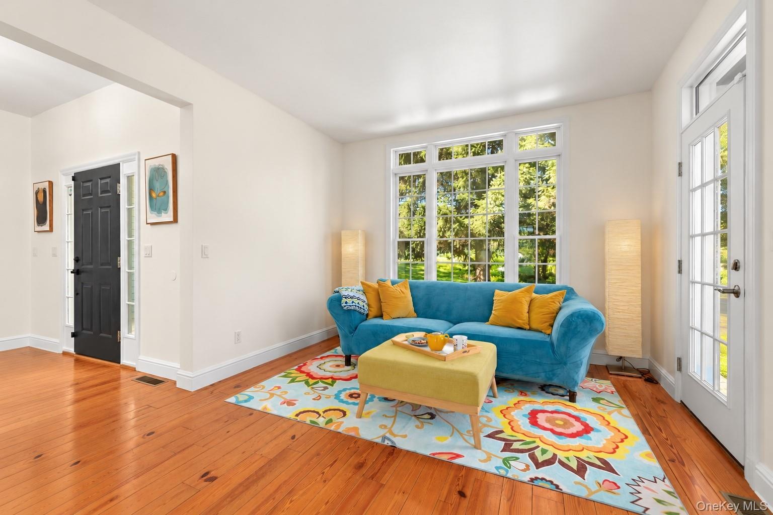This beautifully appointed, sunlit room features gleaming pinewood floors, expansive windows, and glass doors extending the living space outdoors