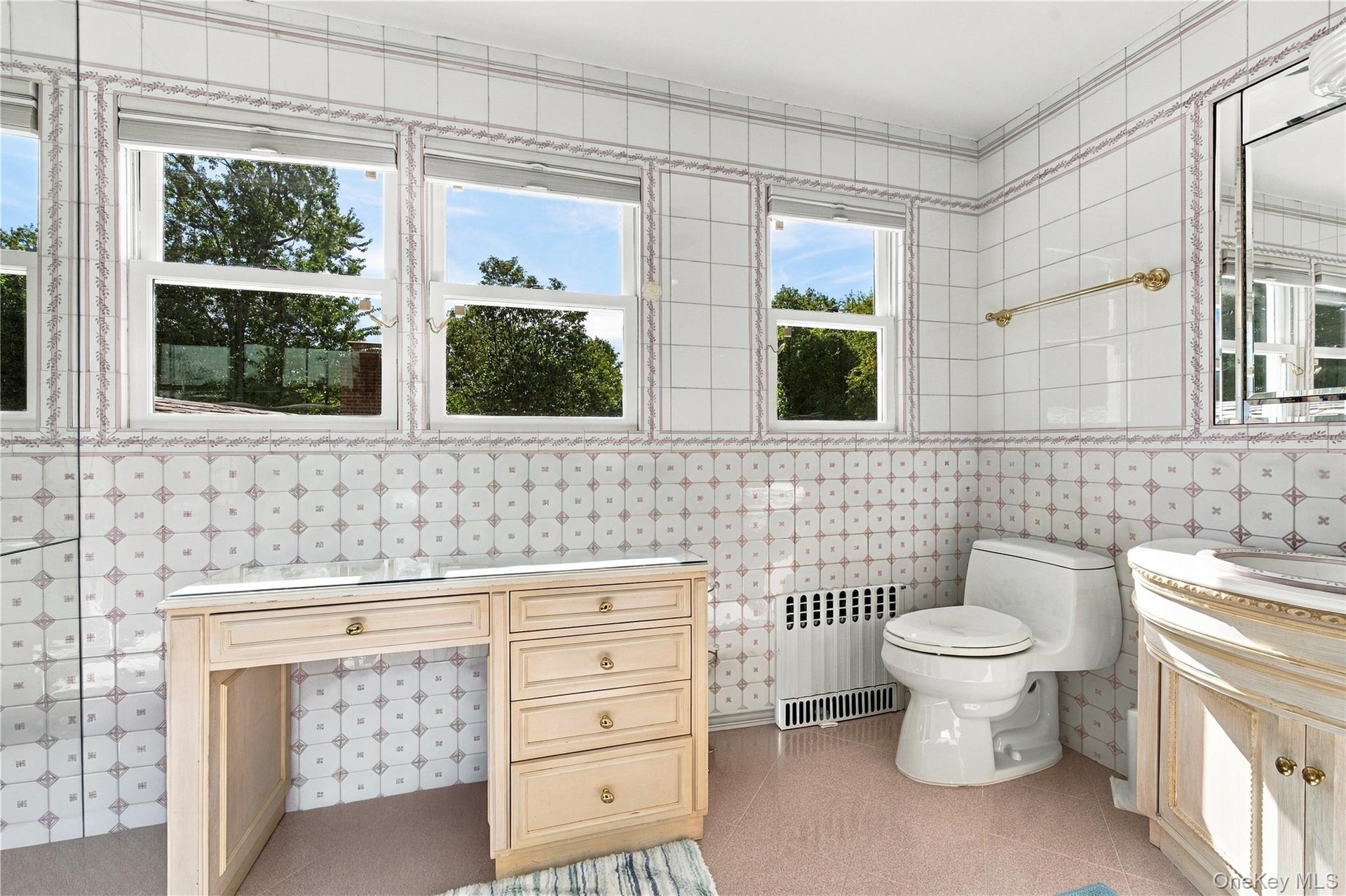 Bathroom featuring floor-to-ceiling decorative tile walls, built-in vanity cabinetry, and three large windows