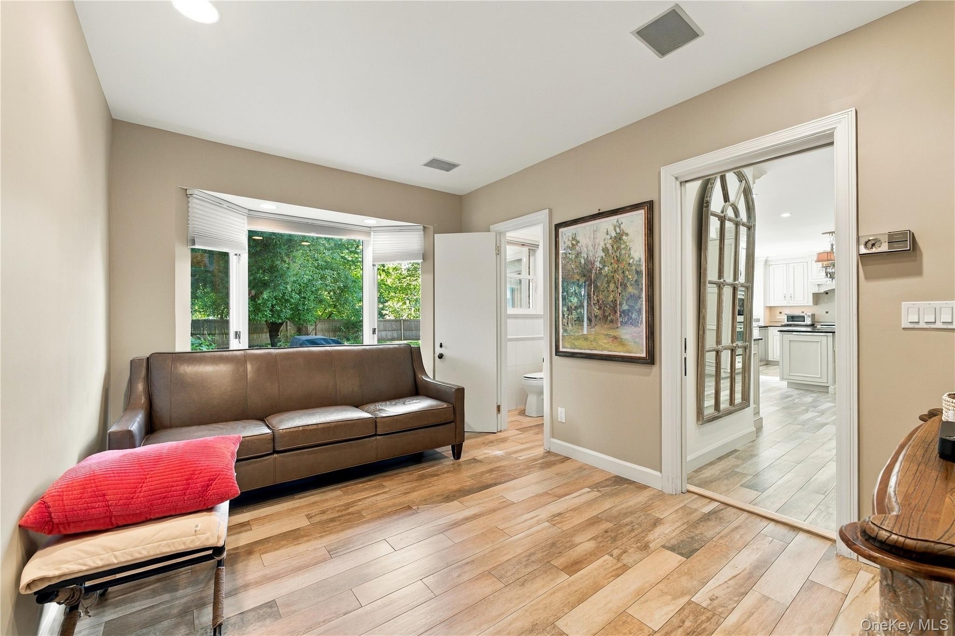 Room featuring wood-finish flooring, a large bay window, and a wide doorway opening to a secondary space