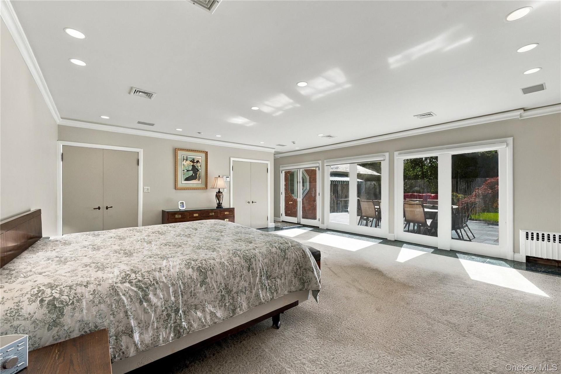 Expansive room featuring recessed lighting, dual closets, and three sets of double glass doors
