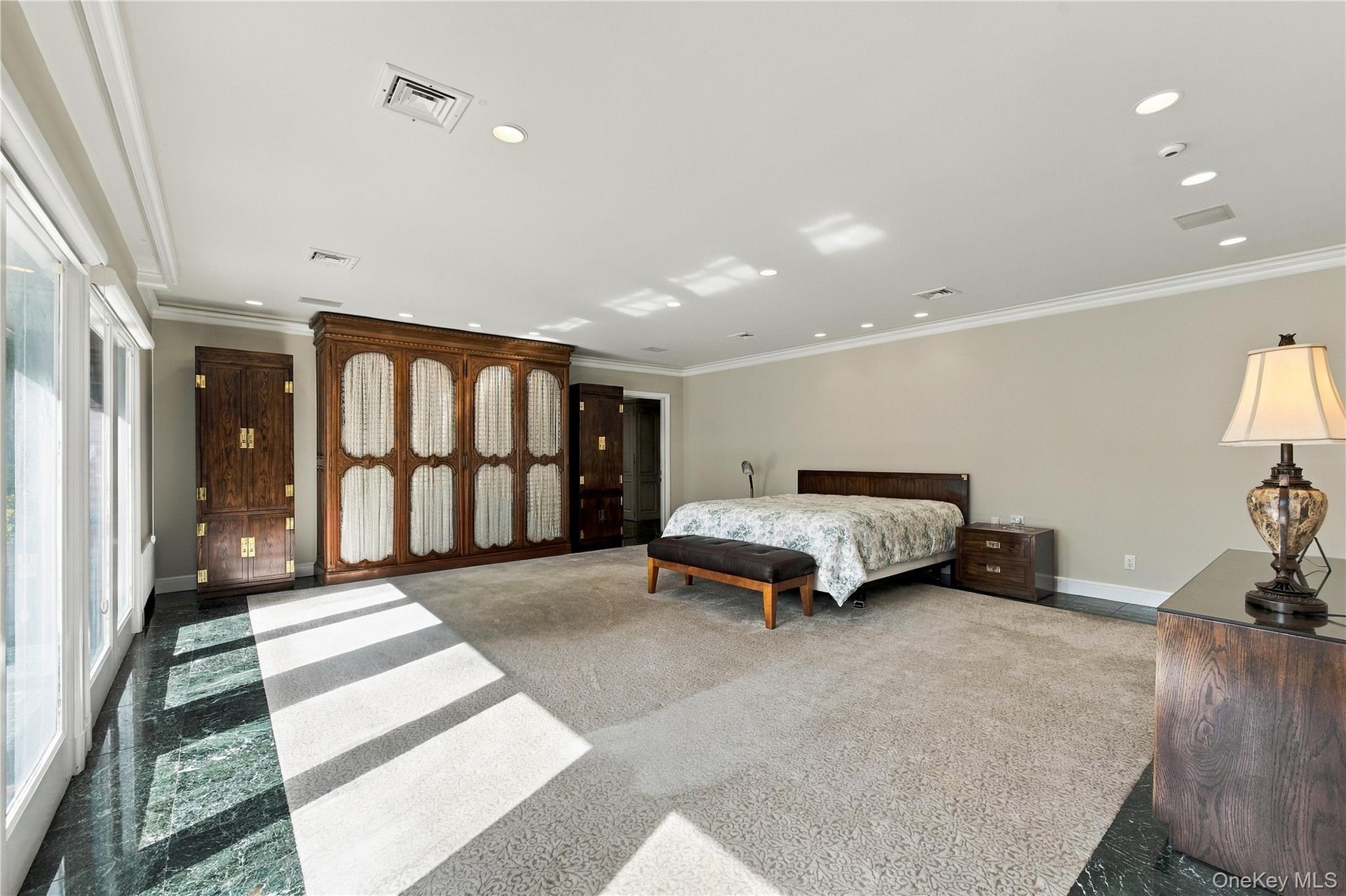 Expansive room featuring built-in floor-to-ceiling wooden cabinetry, polished stone flooring, recessed ceiling lighting, and sliding glass doors
