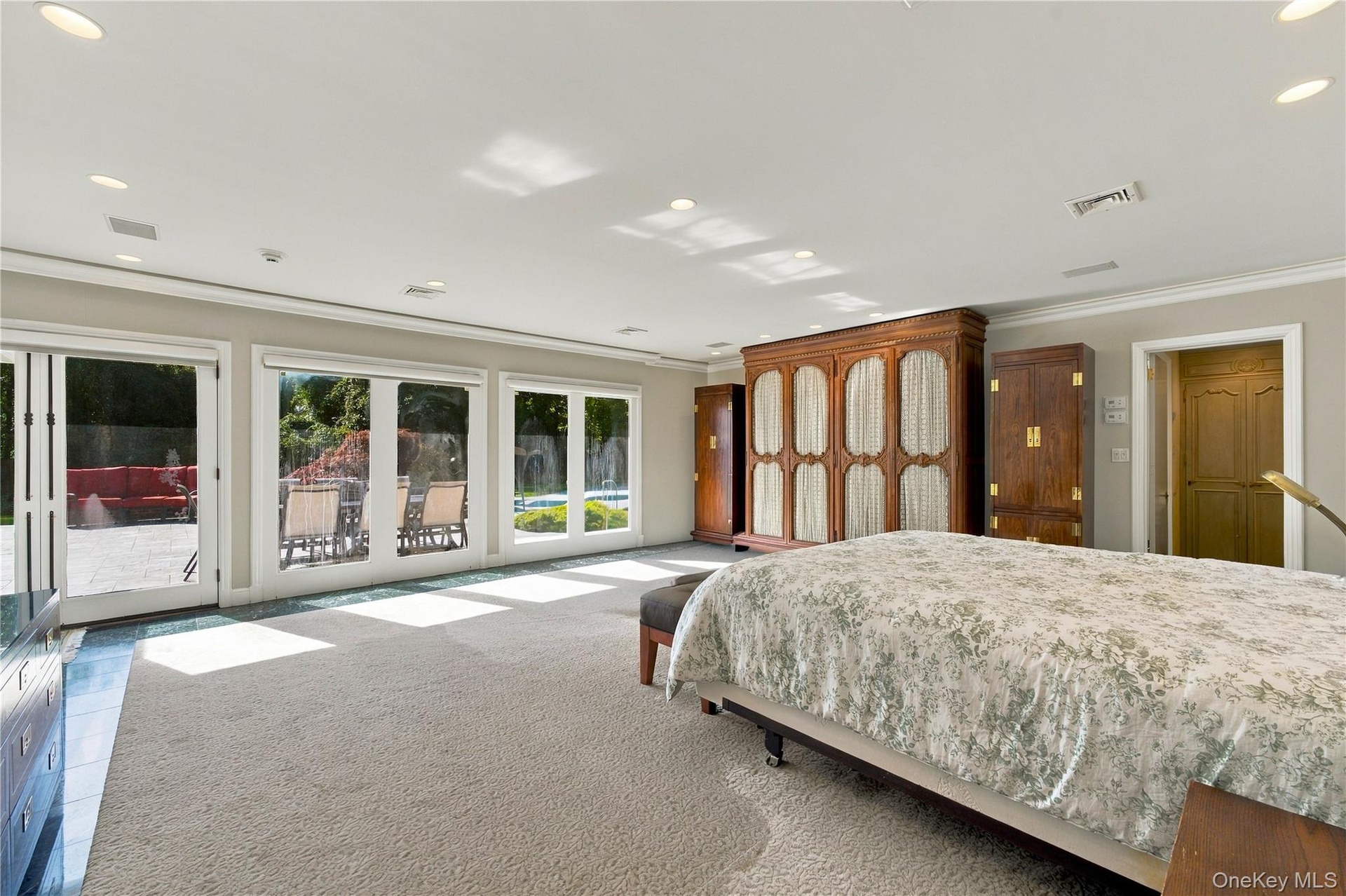 Spacious room with neutral wall-to-wall carpeting, recessed ceiling lighting, three sets of glass patio doors, and built-in wood cabinetry