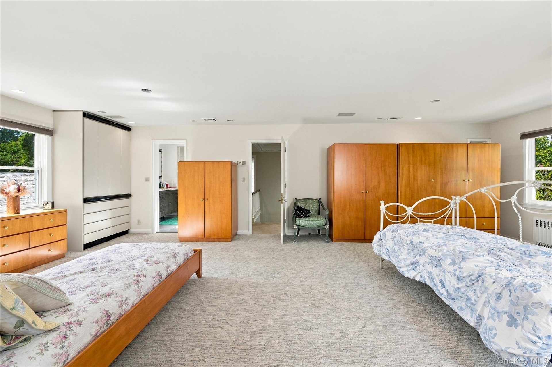 Spacious room featuring neutral carpeting, recessed lighting, double-hung windows, and built-in floor-to-ceiling cabinetry