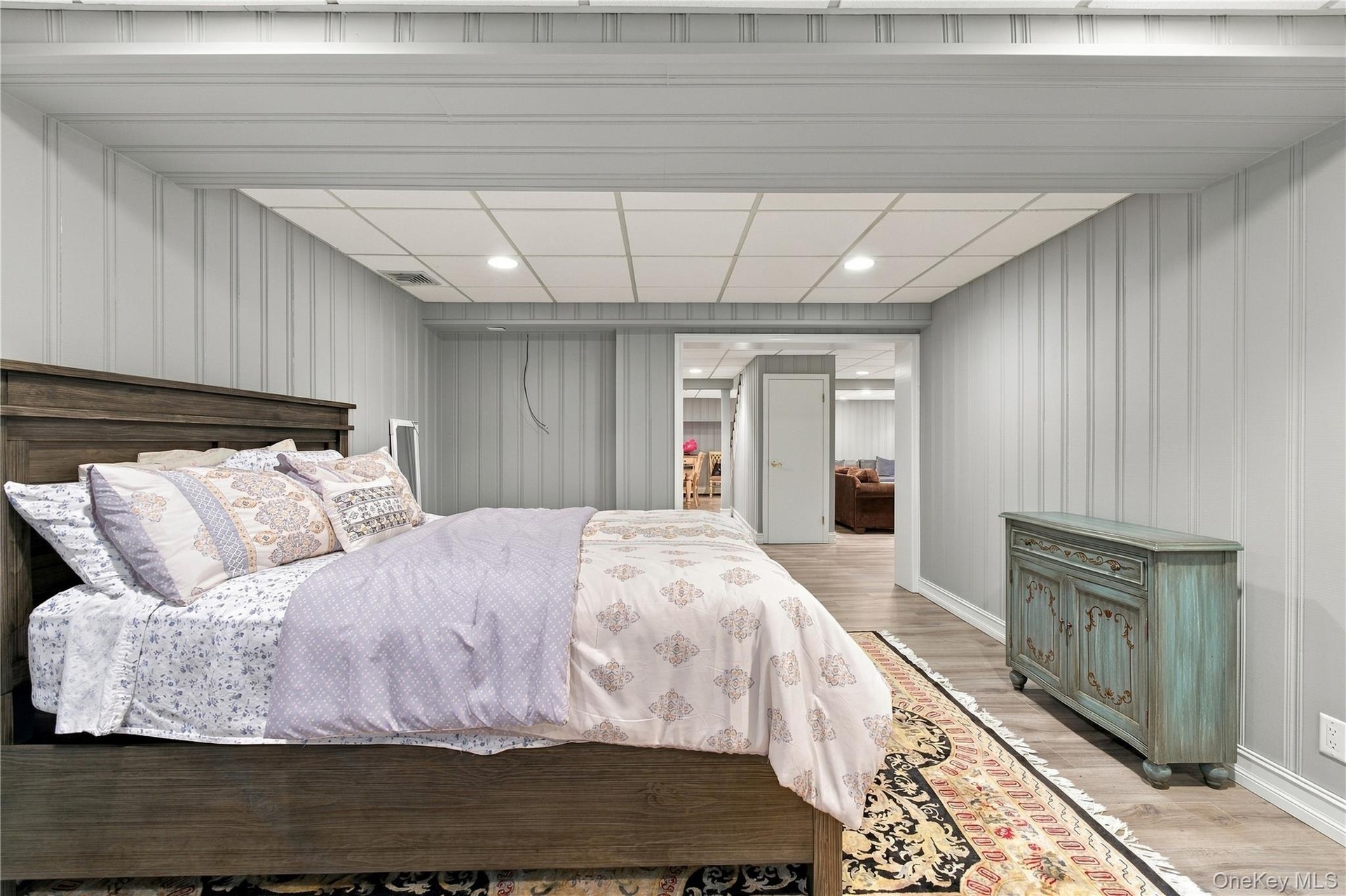 Finished room featuring vertical paneled walls, recessed ceiling lighting, a drop-ceiling grid, and wood-finish flooring