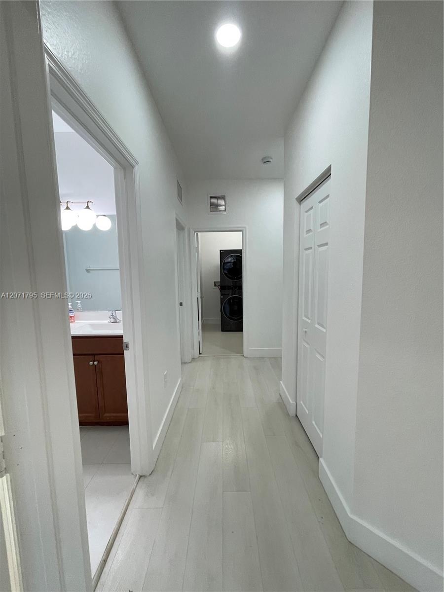 Hallway featuring light-toned wood-finish flooring, recessed lighting, and white six-panel closet doors