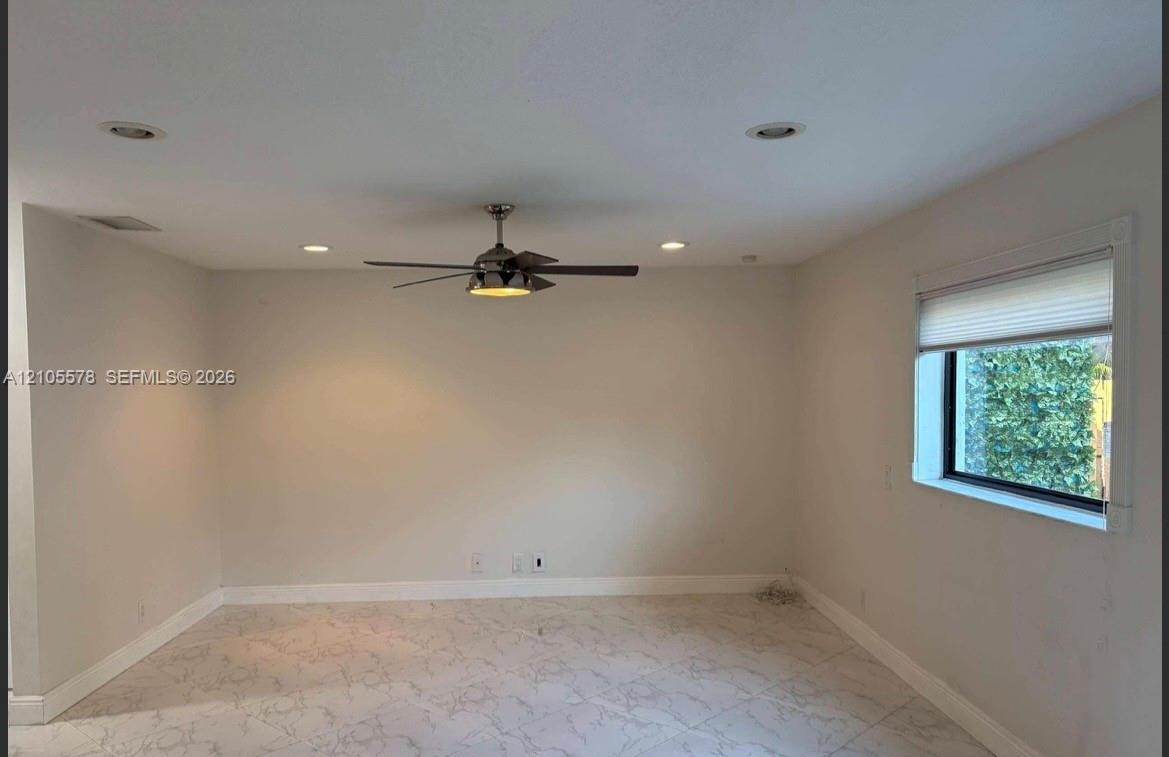 Interior space featuring neutral wall paint, recessed lighting, a ceiling fan with integrated lighting, large-format tile flooring, and a window with 