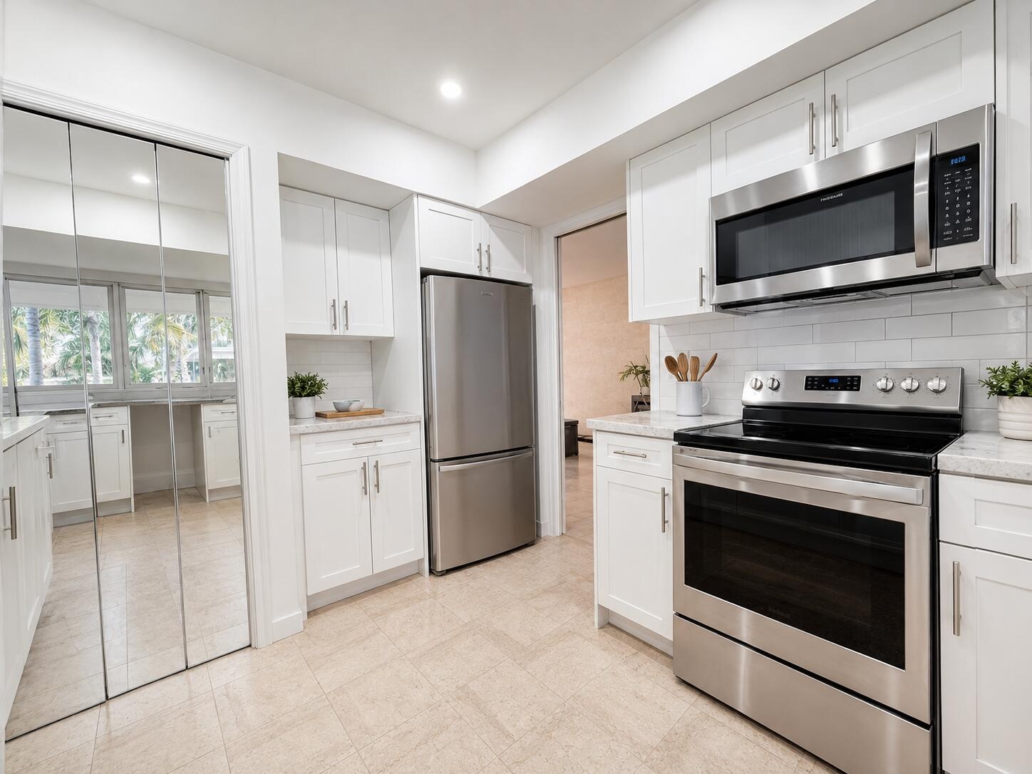 Kitchen featuring white shaker cabinetry, stainless steel appliances, light-toned tile flooring, white subway tile backsplash, and light-toned counter
