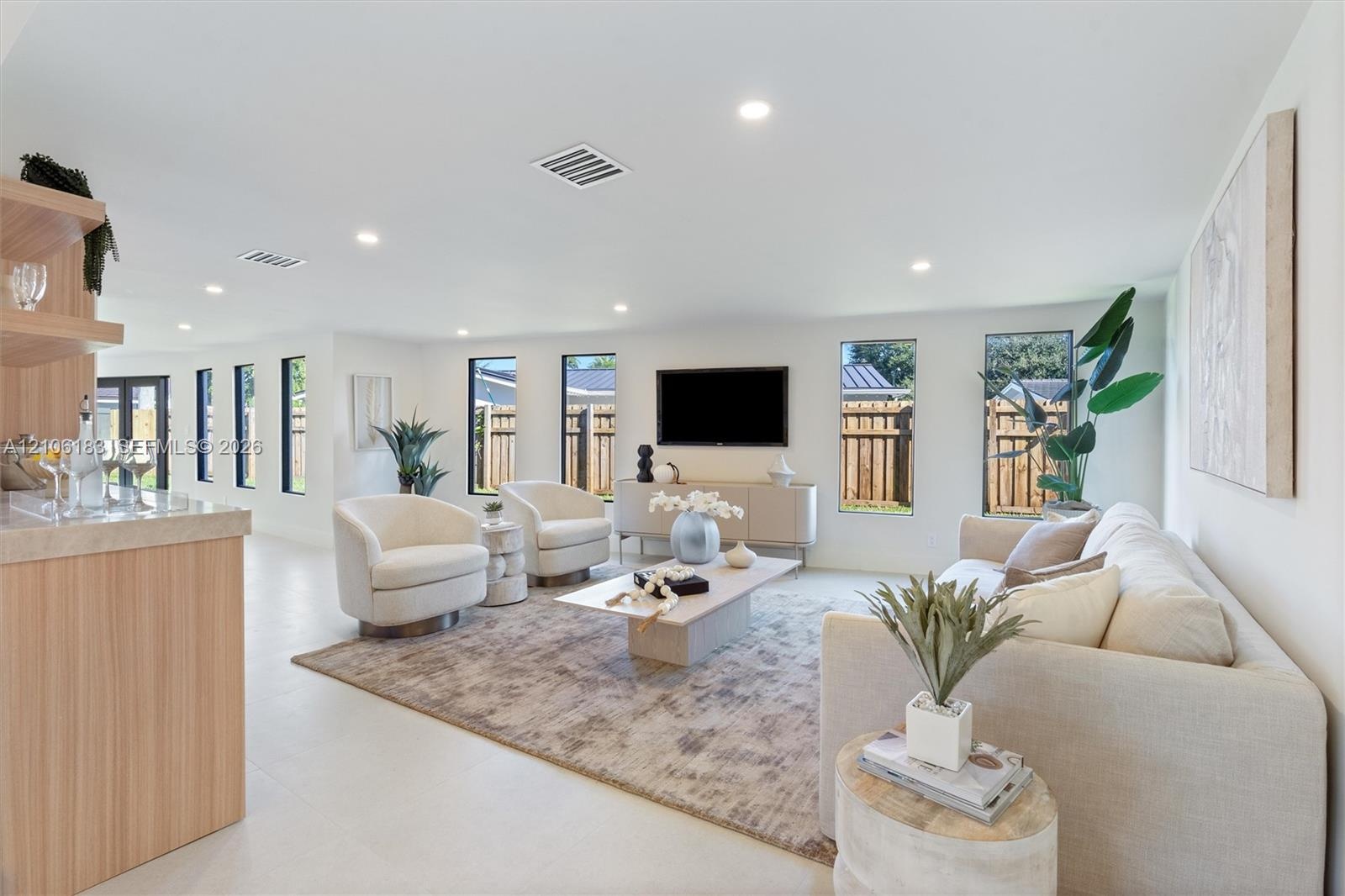 Open-concept interior featuring light-toned tile flooring, recessed ceiling lighting, vertical windows, and a built-in cabinetry unit