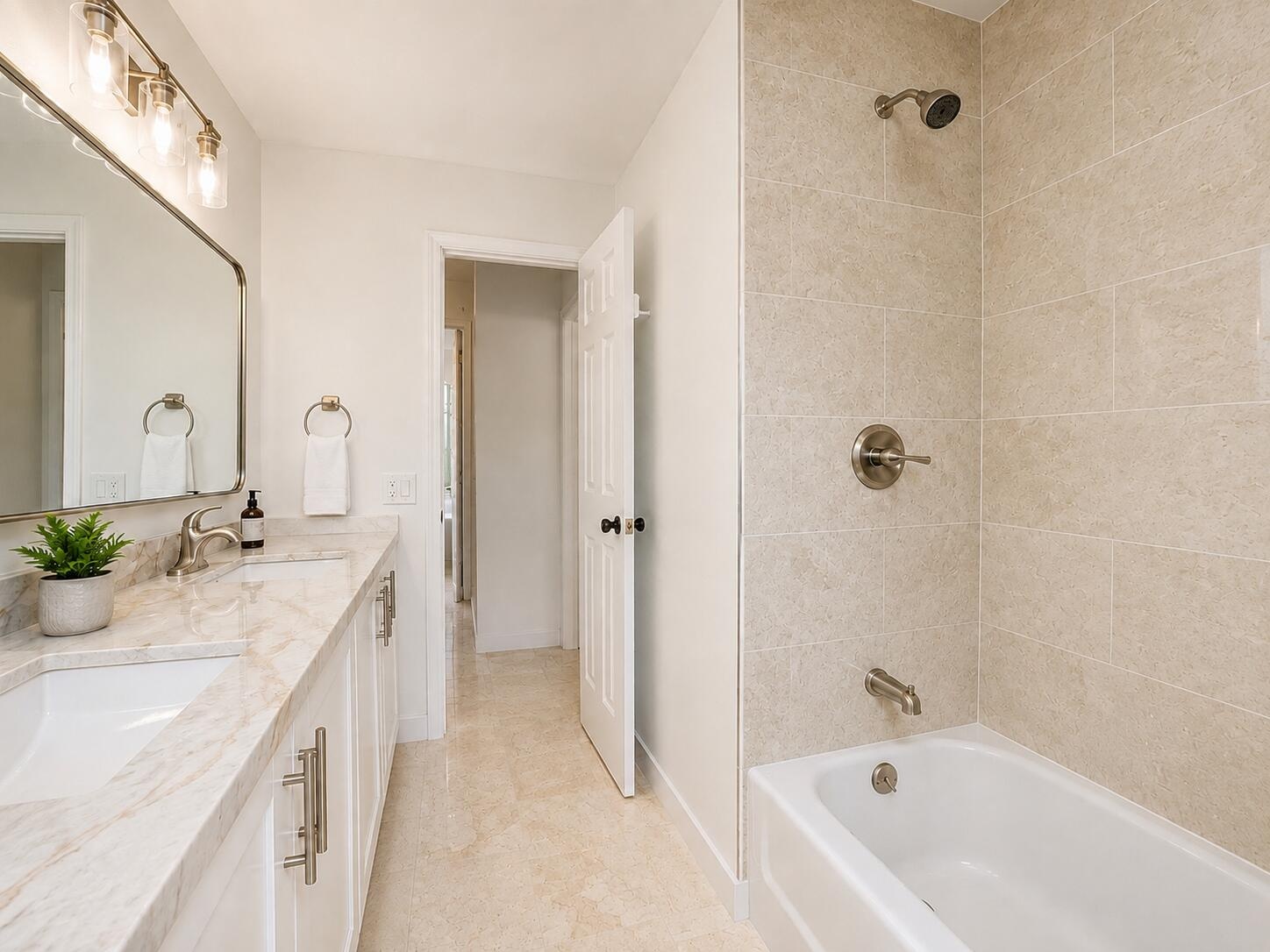 White vanity with brushed nickel hardware, a rectangular undermount sink, and a stone countertop