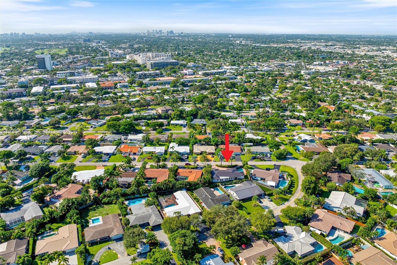 Aerial perspective of a residential property featuring a low-pitch roof, a multi-car driveway, and mature landscaping