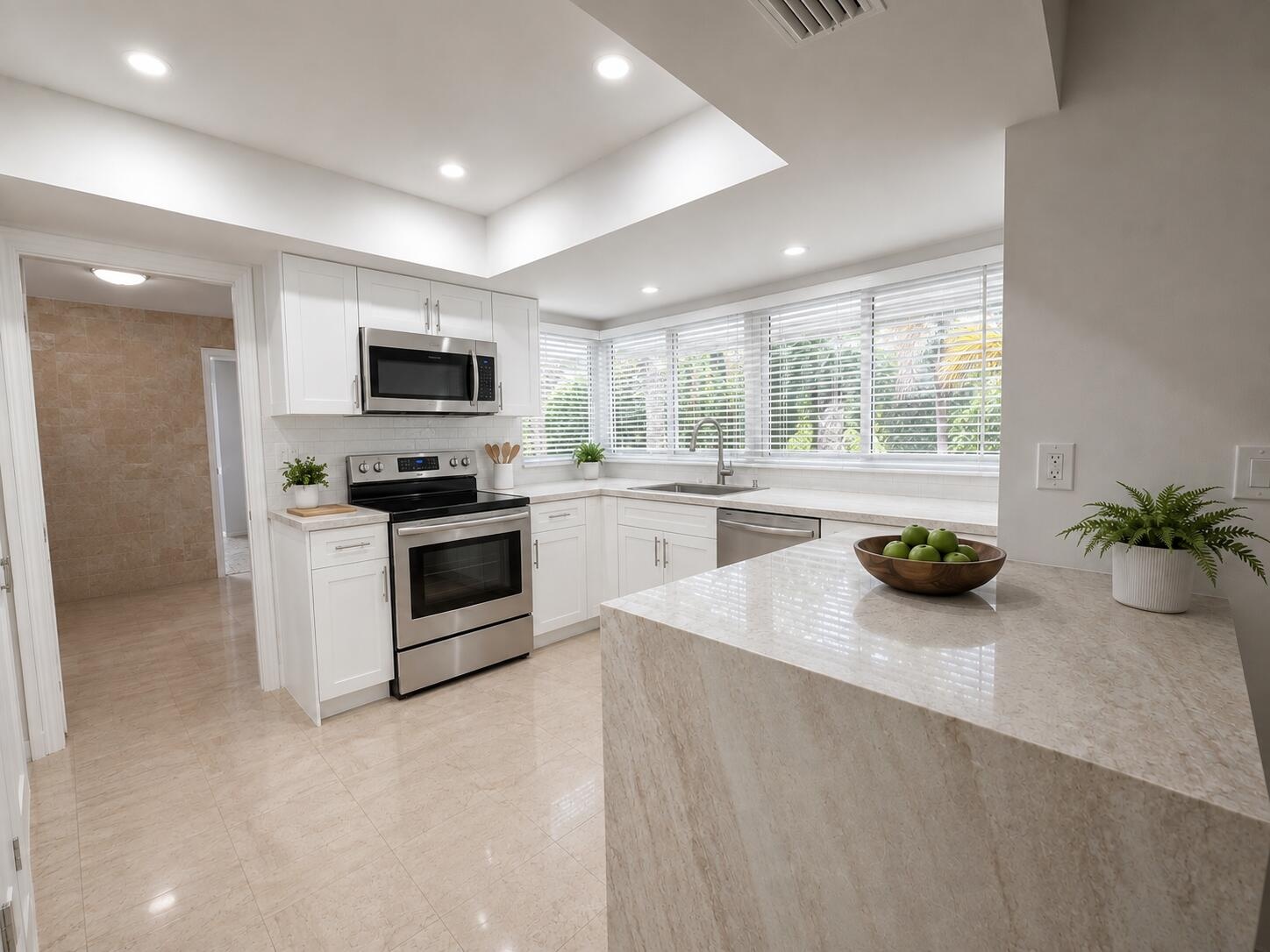 Modern kitchen featuring white cabinetry, stainless steel appliances, a breakfast bar, and multiple windows with blinds