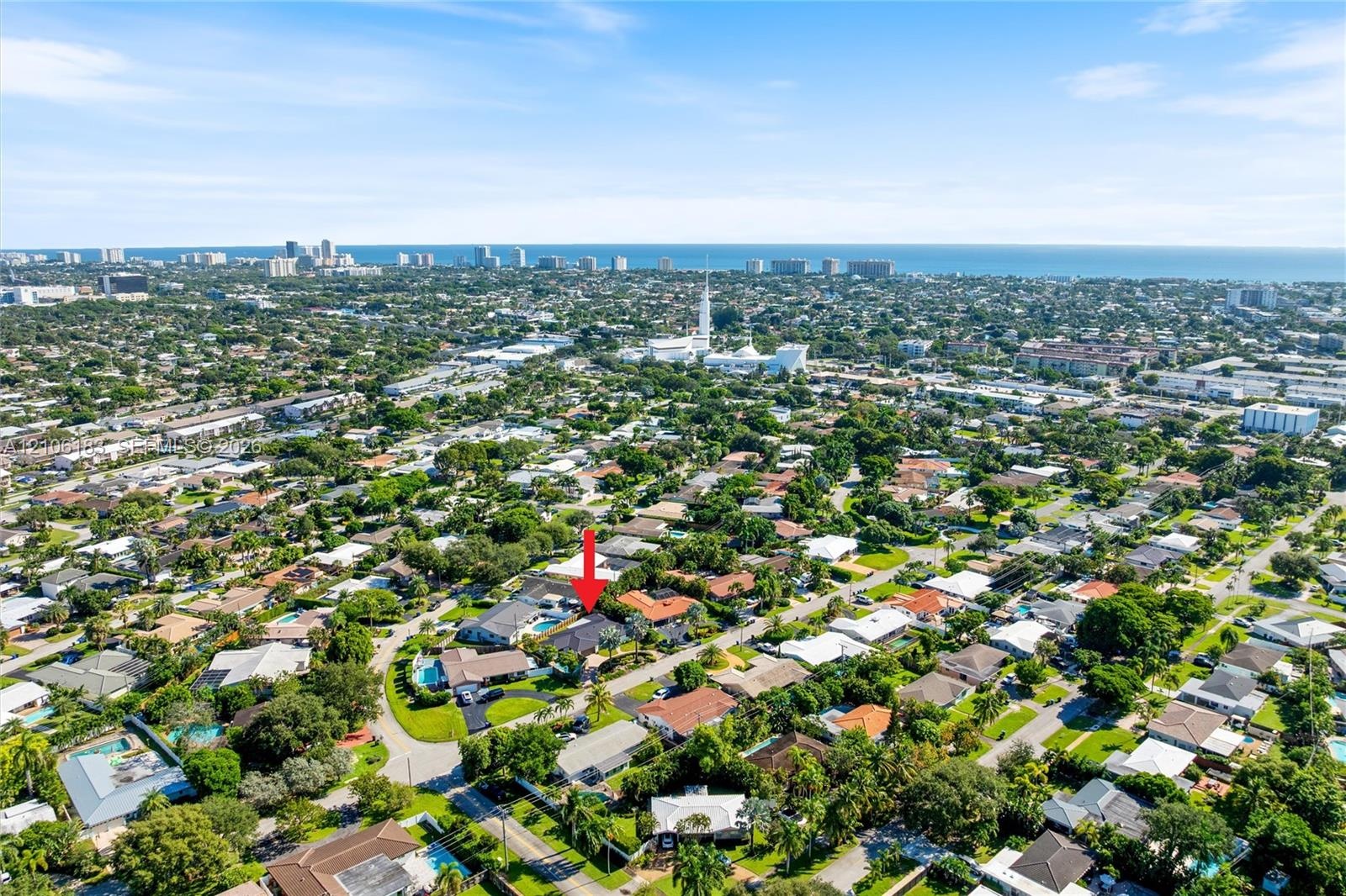 Aerial perspective showcasing a residential property with a swimming pool, mature perimeter landscaping, and proximity to the coastline
