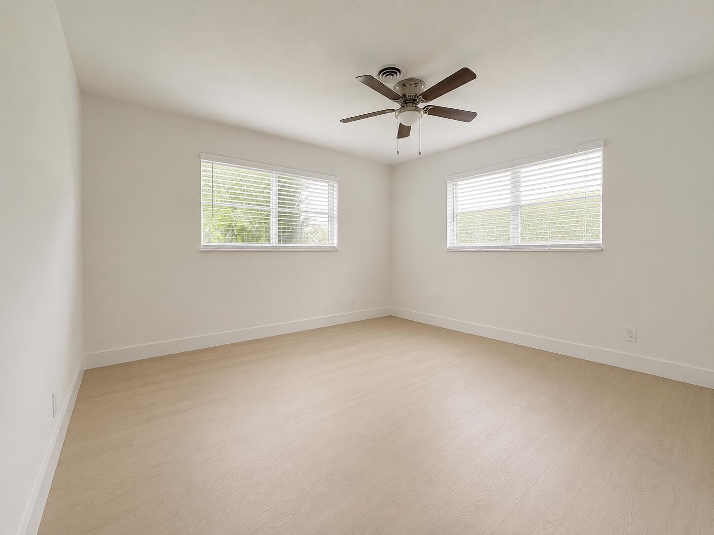 Recessed ceiling fan, two windows with blinds, wood-finish flooring, and white walls