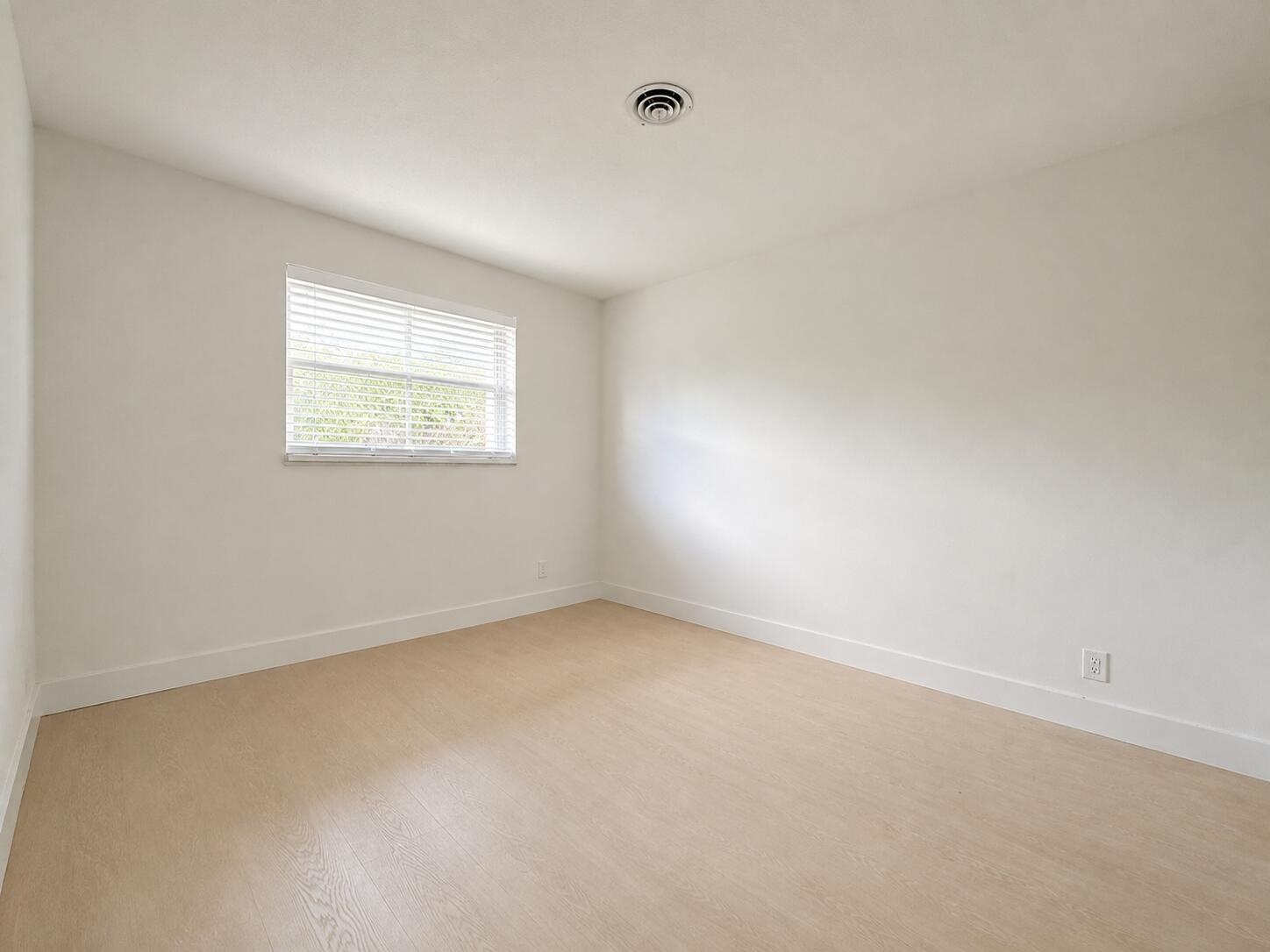 Neutral wall finishes with wood-finish flooring and a single window with blinds