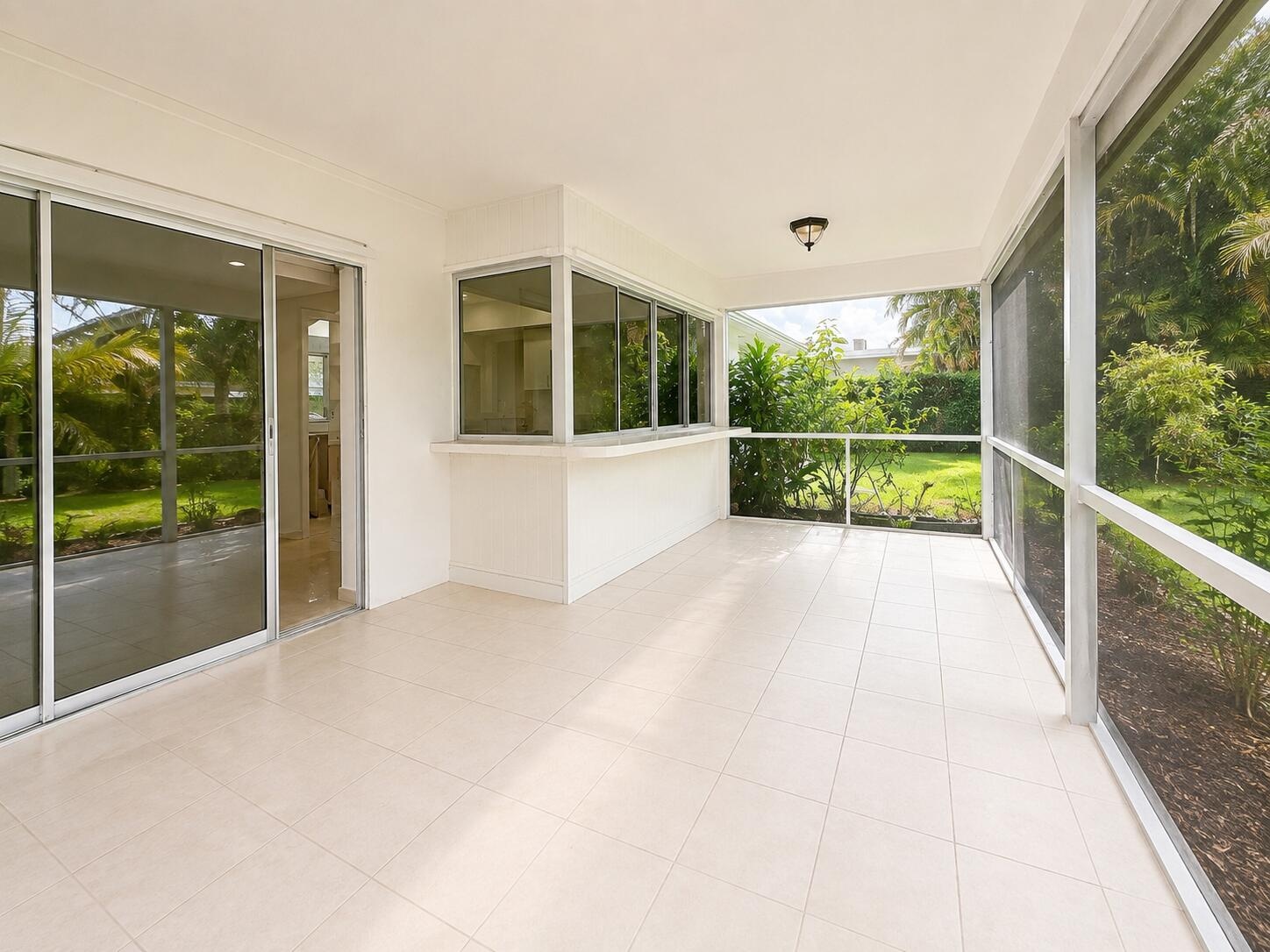 Screened patio featuring tile flooring, a built-in counter, and sliding glass door access