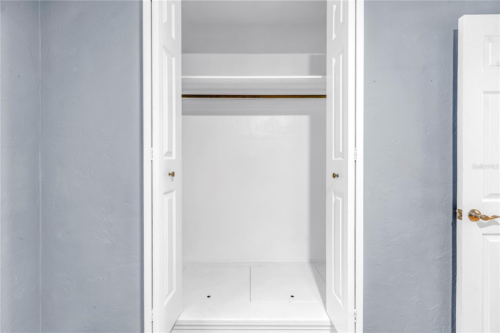 Third bedroom featuring a spacious closet with hidden floor-level storage.