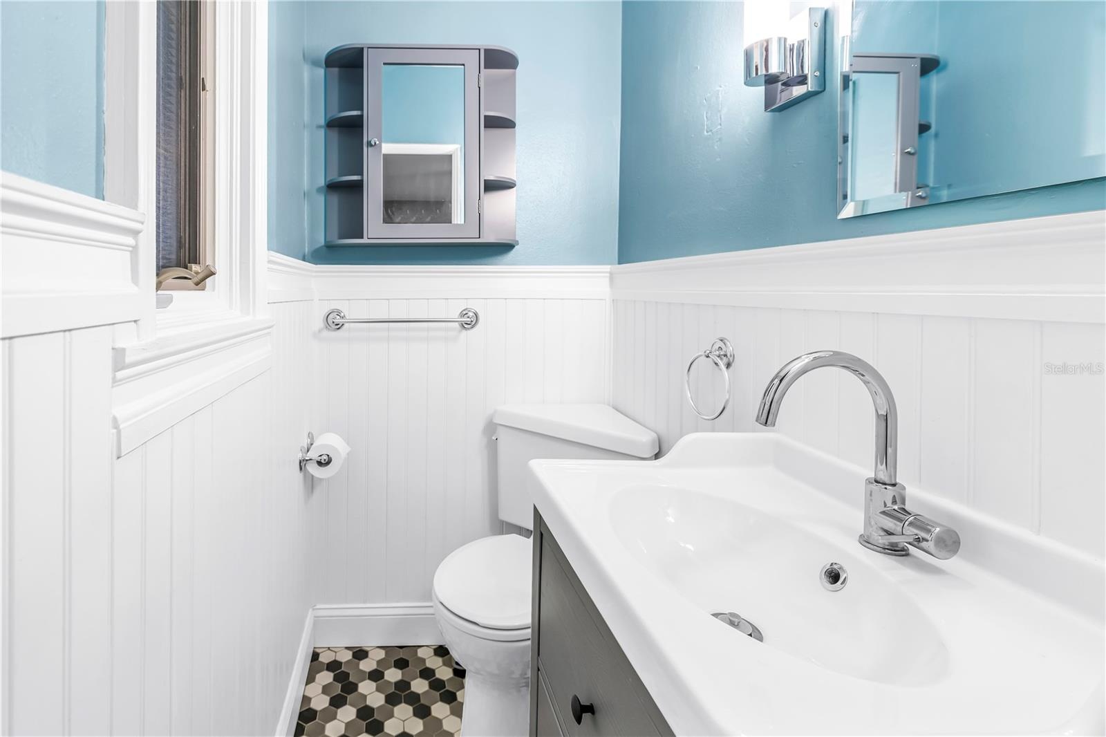 This is the second bedroom's half bath, featuring charming beadboard paneling and elegant fixtures.