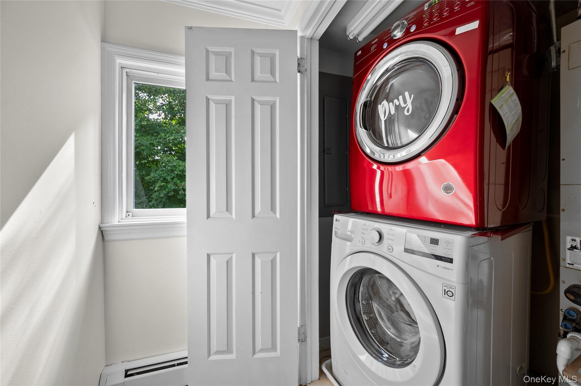 Utility space featuring stacked appliances, a single-hung window with casing, and a four-panel interior door