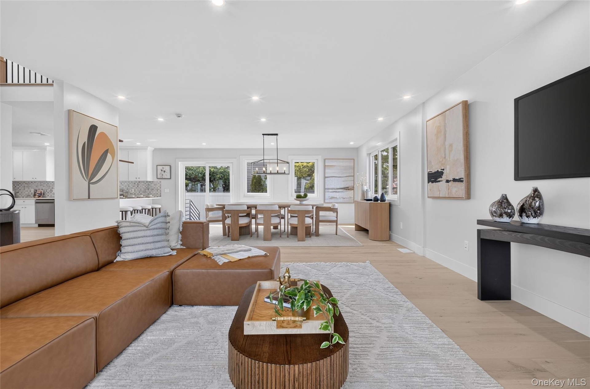 Open-concept interior featuring light wood-finish flooring, recessed lighting, and a geometric chandelier