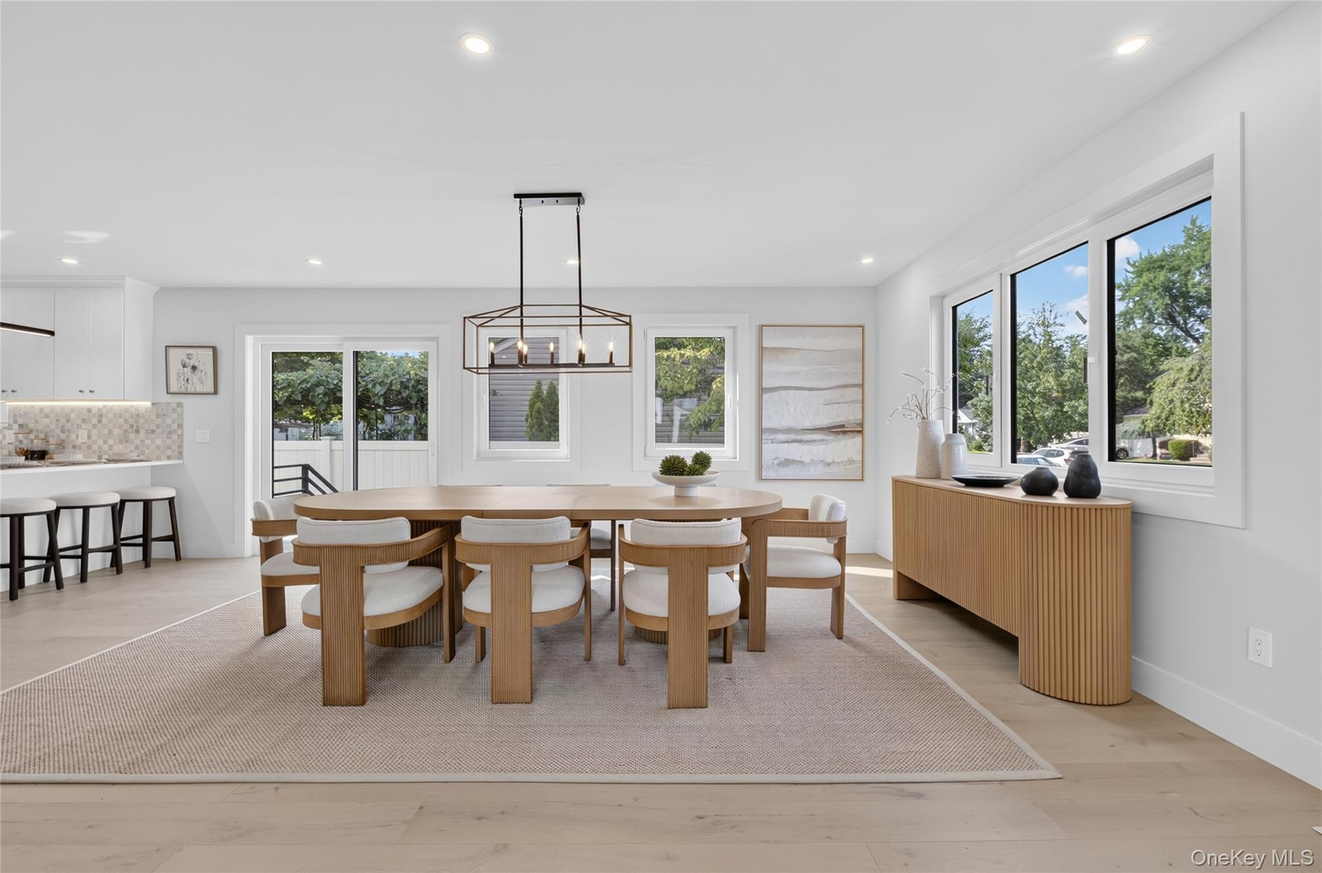 Dining area featuring wood-finish flooring, recessed lighting, a modern geometric chandelier, large windows, and a sliding glass door