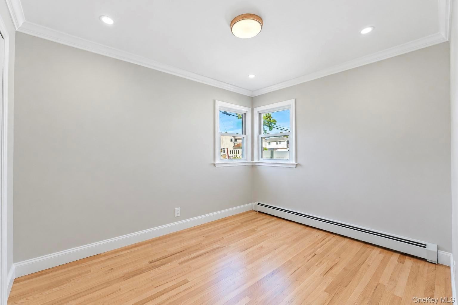 Neutral-toned interior featuring hardwood flooring, crown molding, recessed lighting, and a modern circular flush-mount ceiling fixture