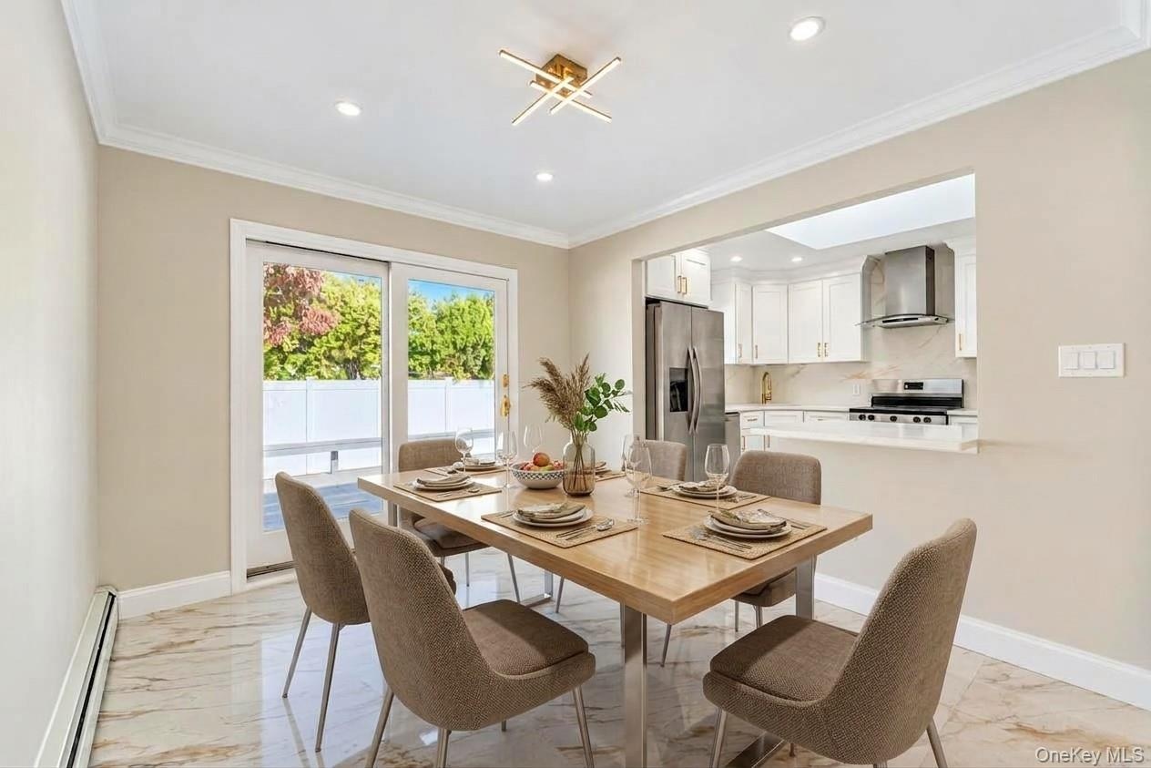 Dining area featuring stone-finish tile flooring, crown molding, modern geometric light fixture, and sliding glass doors with backyard access