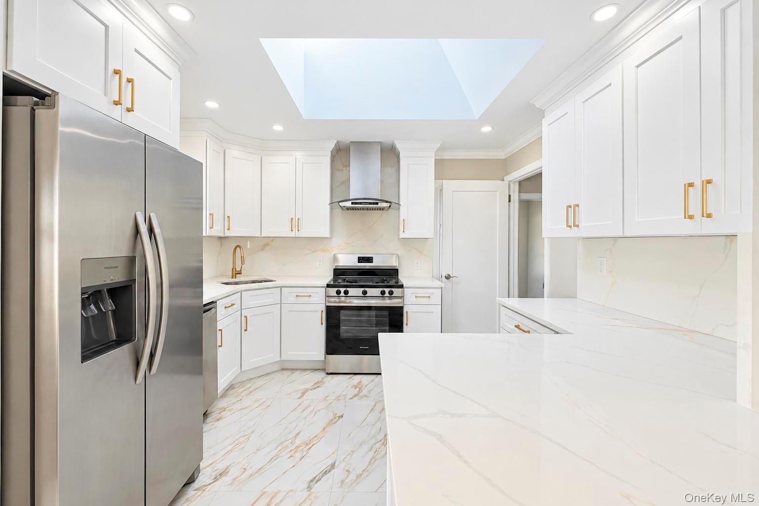 Kitchen featuring white shaker-style cabinetry, stainless steel appliances, quartz countertops, a large skylight, and stone-finish tile flooring
