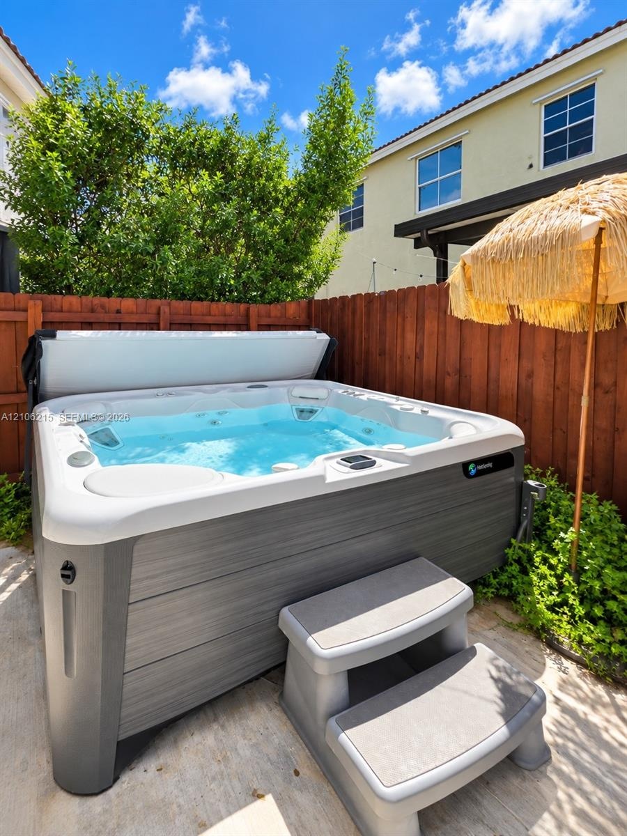 Exterior spa with a gray composite finish, integrated stairs, and a wood privacy fence