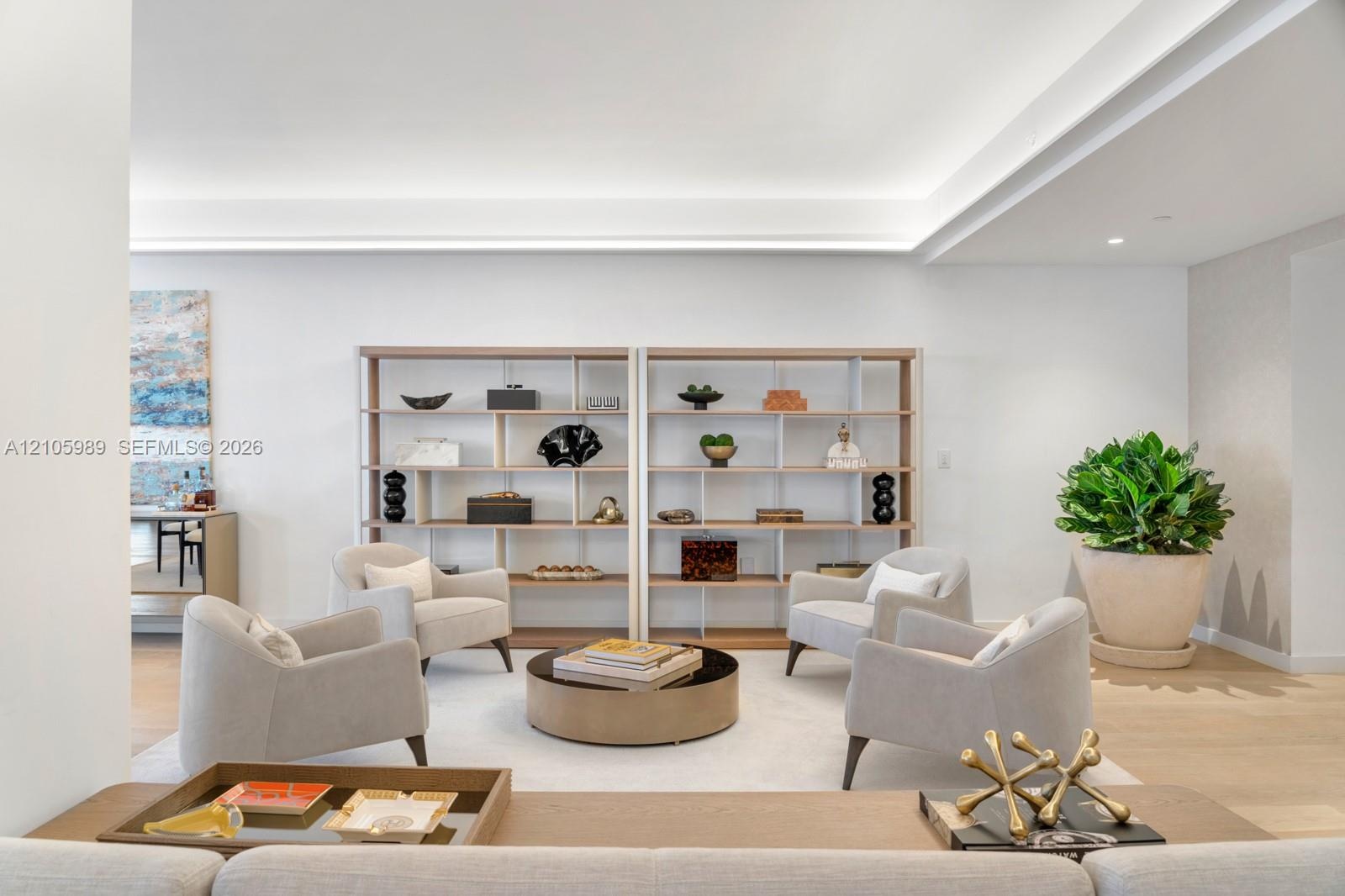 Built-in floor-to-ceiling shelving, recessed tray ceiling with cove lighting, and neutral wood-finish flooring