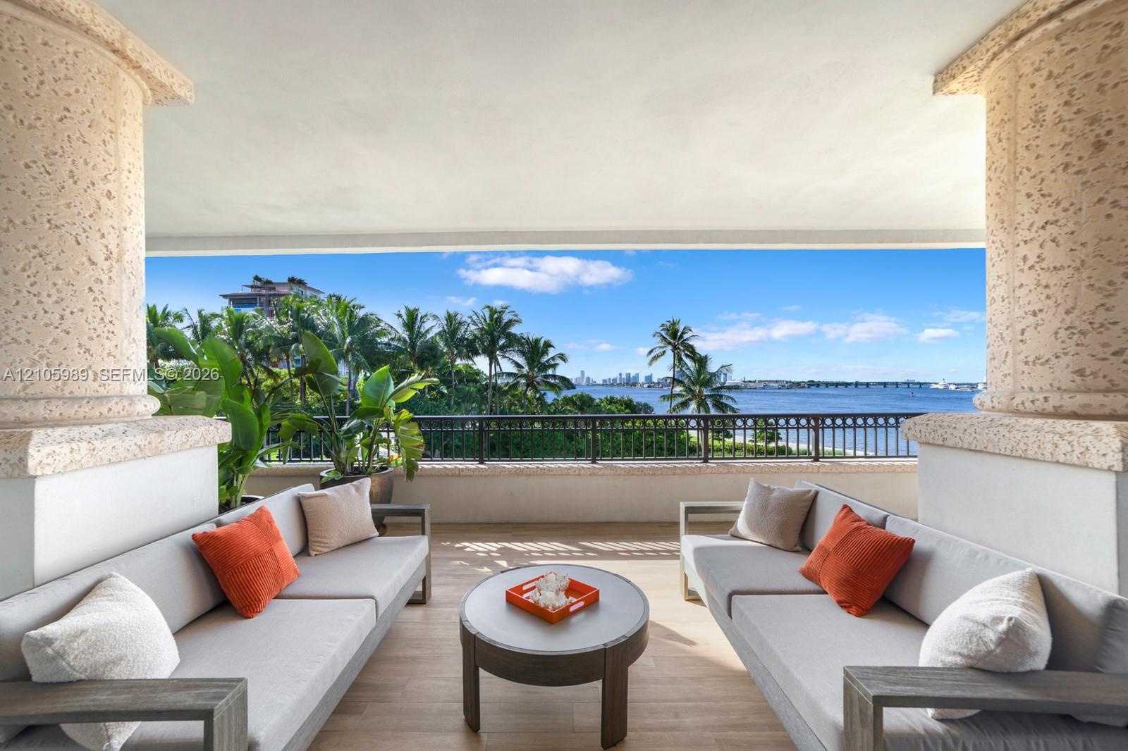 Covered terrace featuring natural stone columns, tile flooring, and a metal railing