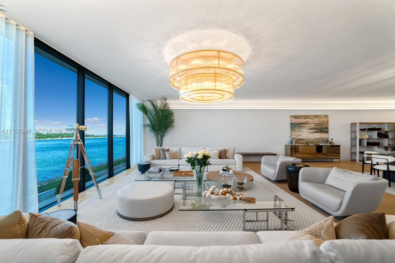 Floor-to-ceiling glass windows, tiered crystal chandelier, cove lighting, and wood-finish flooring