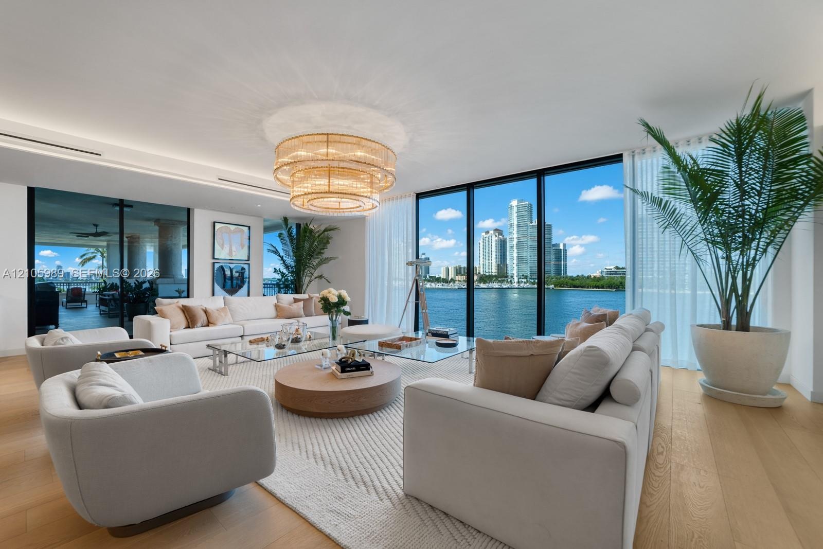 Living area featuring floor-to-ceiling glass walls, wood-finish flooring, multi-tier circular chandelier, and recessed lighting