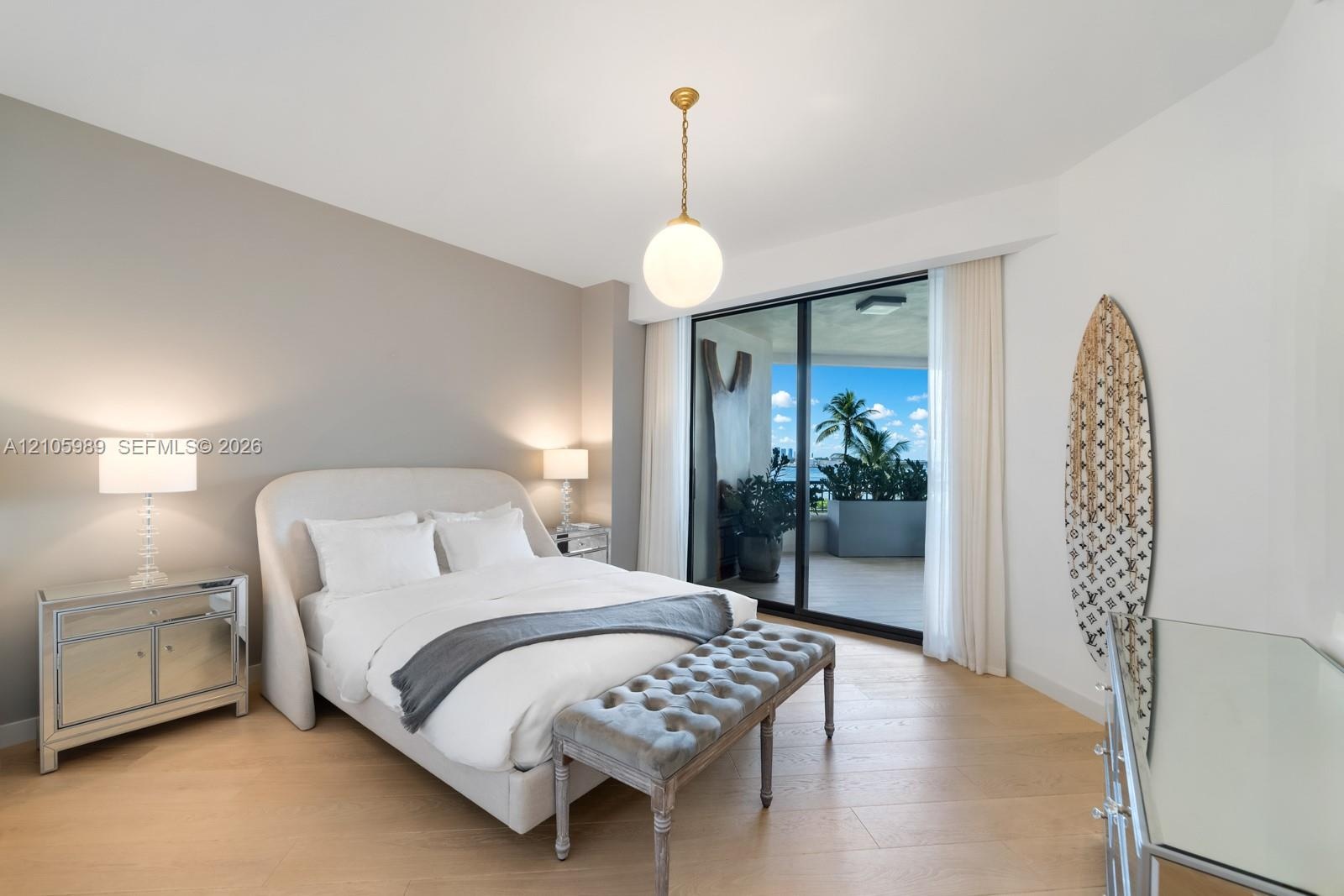 Light-filled room featuring wood-finish flooring, a globe pendant light fixture, and sliding glass doors opening to a covered balcony