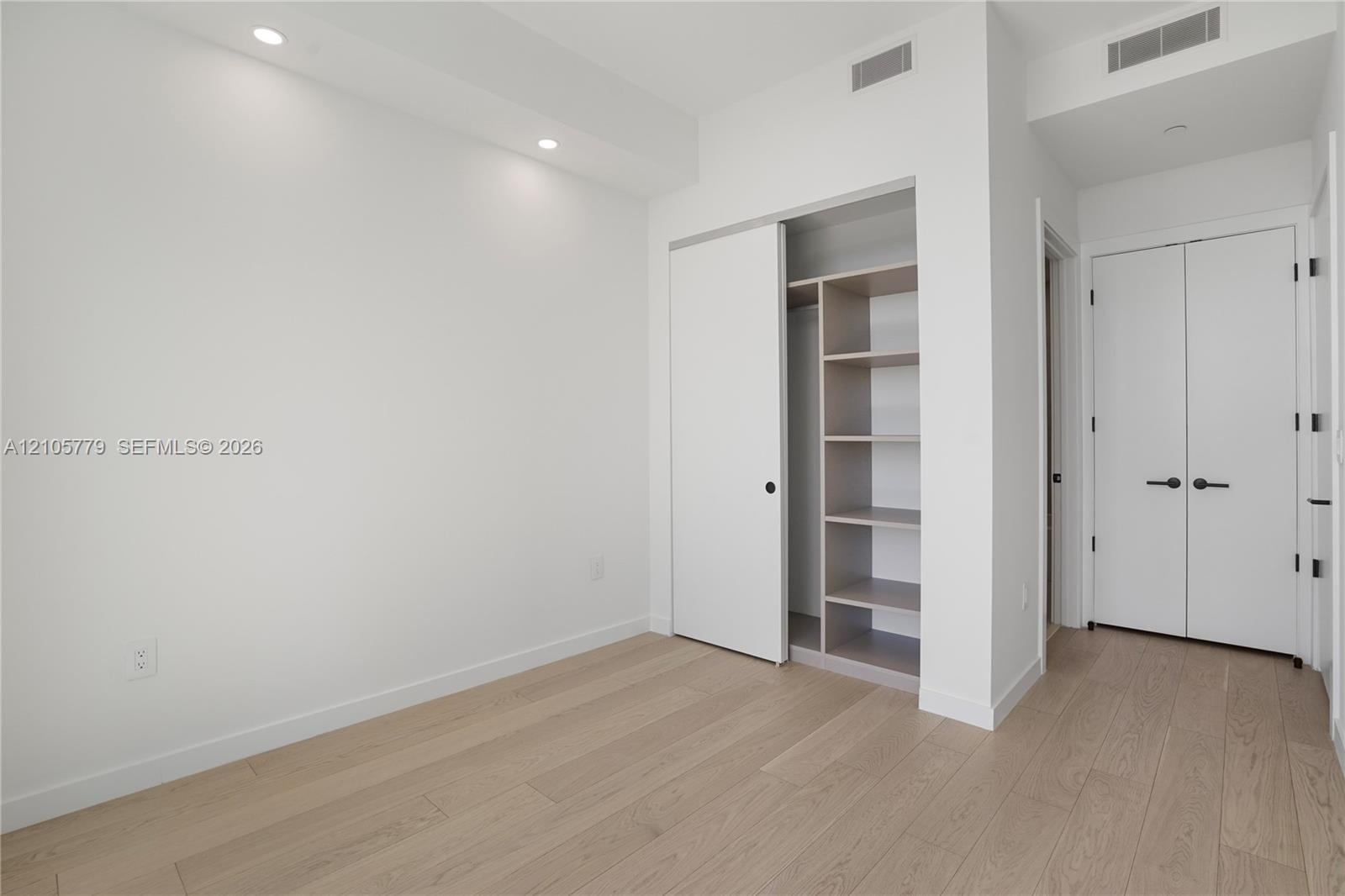 Room featuring wood-finish flooring, recessed lighting, and a closet with built-in shelving