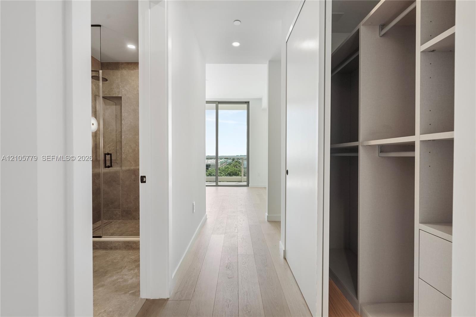 Hallway featuring light-toned wood-finish flooring, recessed lighting, and custom built-in cabinetry with integrated shelving and drawers