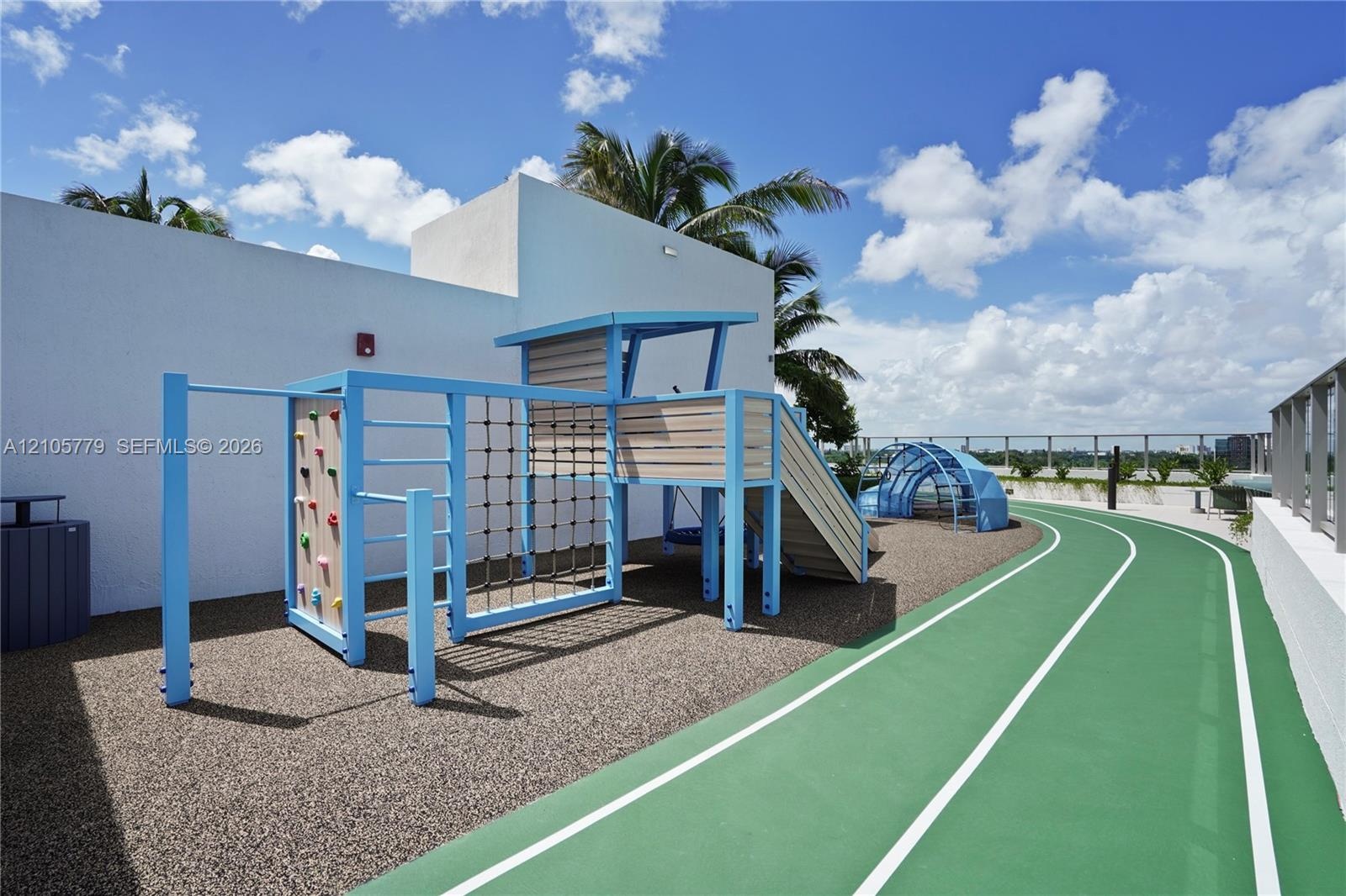 Recreational deck featuring a multi-lane running track, integrated climbing structure with rope netting, dome-style apparatus, and white masonry perim