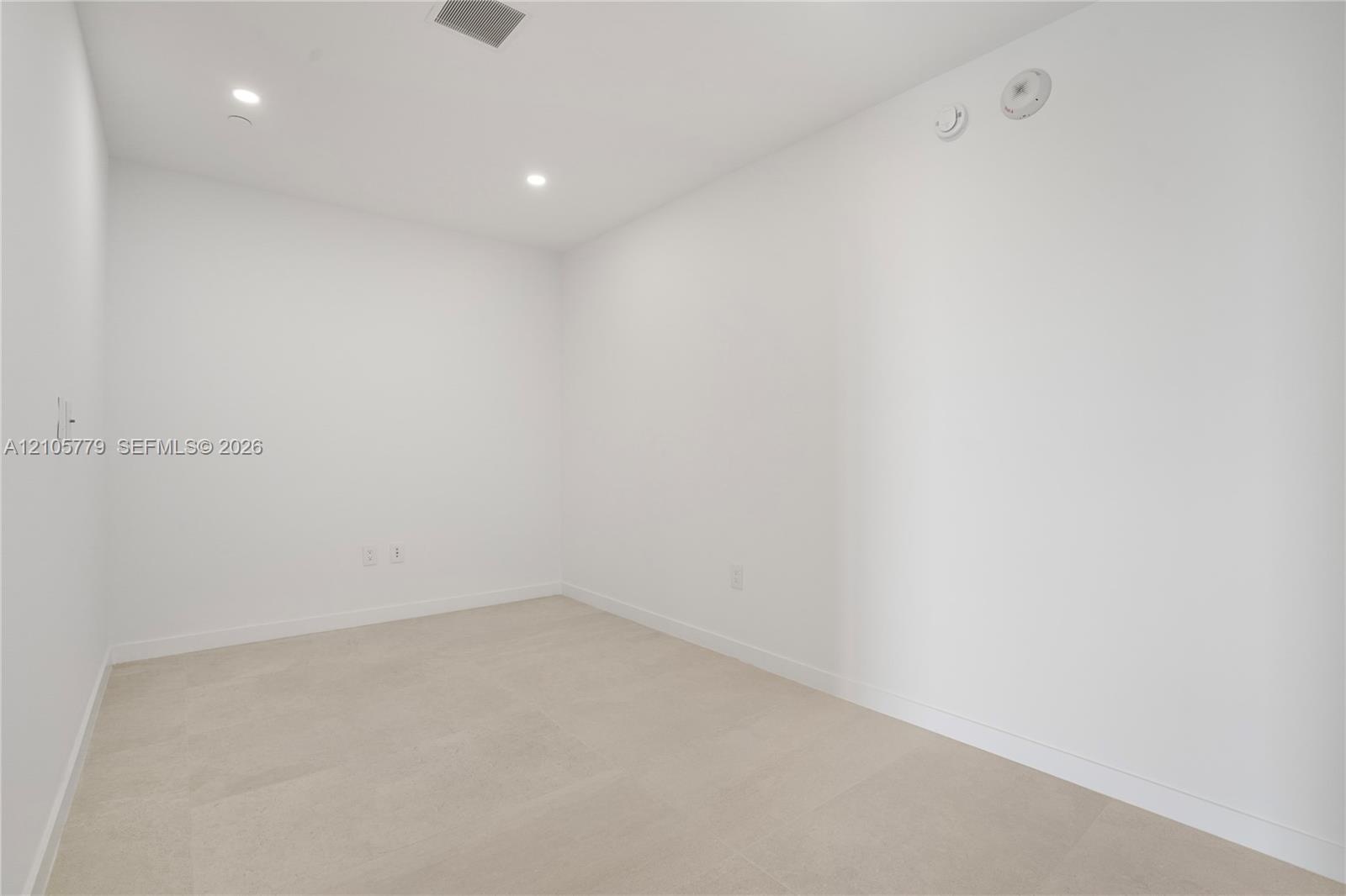 Interior space featuring neutral stone-finish flooring, crisp white walls, and recessed ceiling lighting