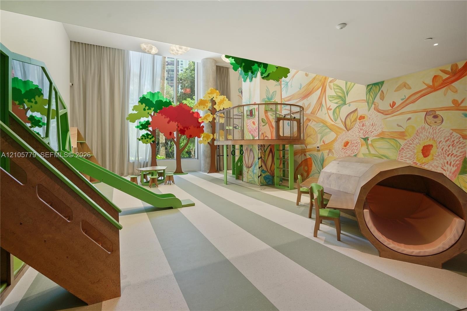 Recreational space featuring custom built-in wood climbing structures, integrated slide, large-scale wall murals, and floor-to-ceiling windows